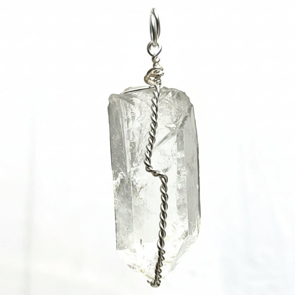 A silver chain necklace featuring a clear, natural pointed crystal pendant with a twisted silver wire wrapped detail, shown against a textured white background.