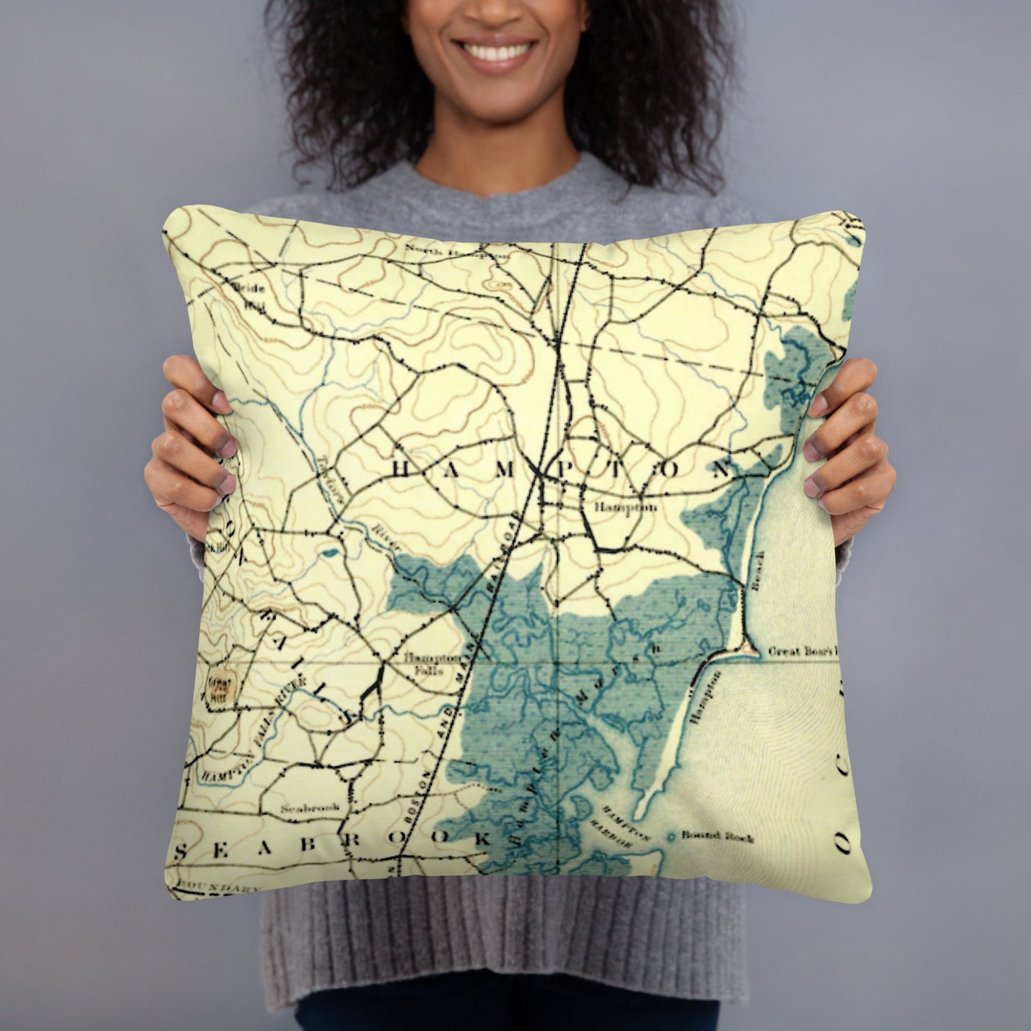 Person holding a pillow with a map design against a gray background