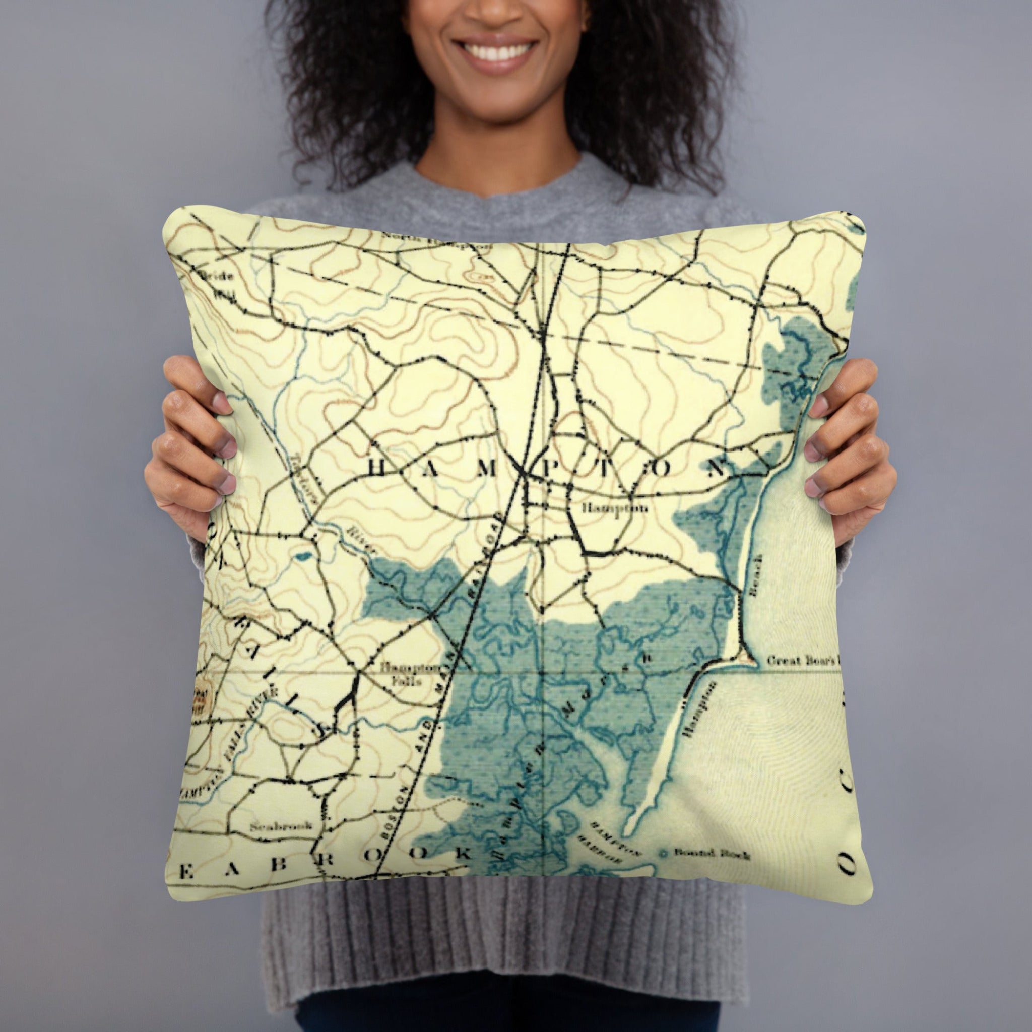 Person holding a map-themed pillow against a gray background