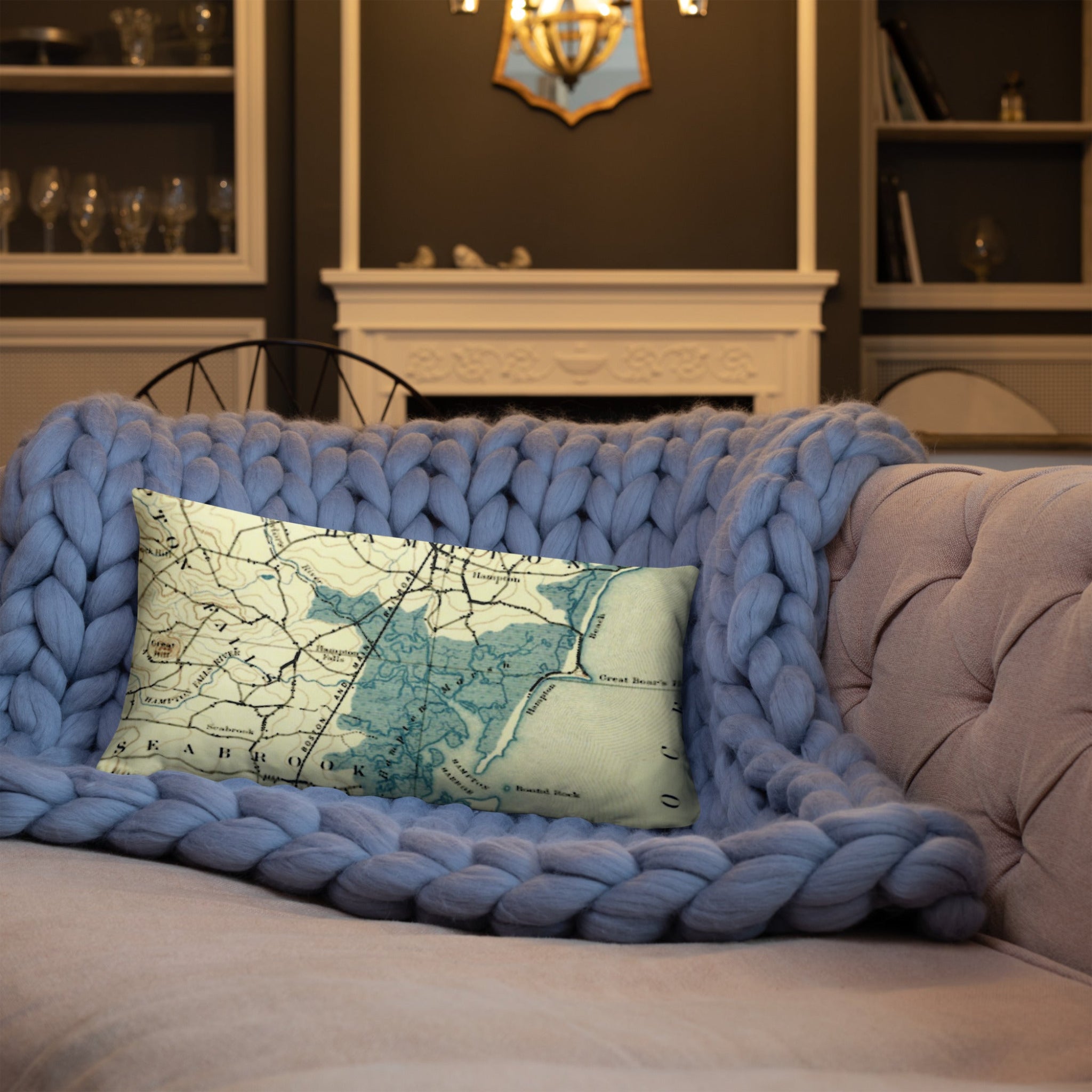 Blue knitted throw blanket draped over a sofa with a decorative pillow featuring a map design.
