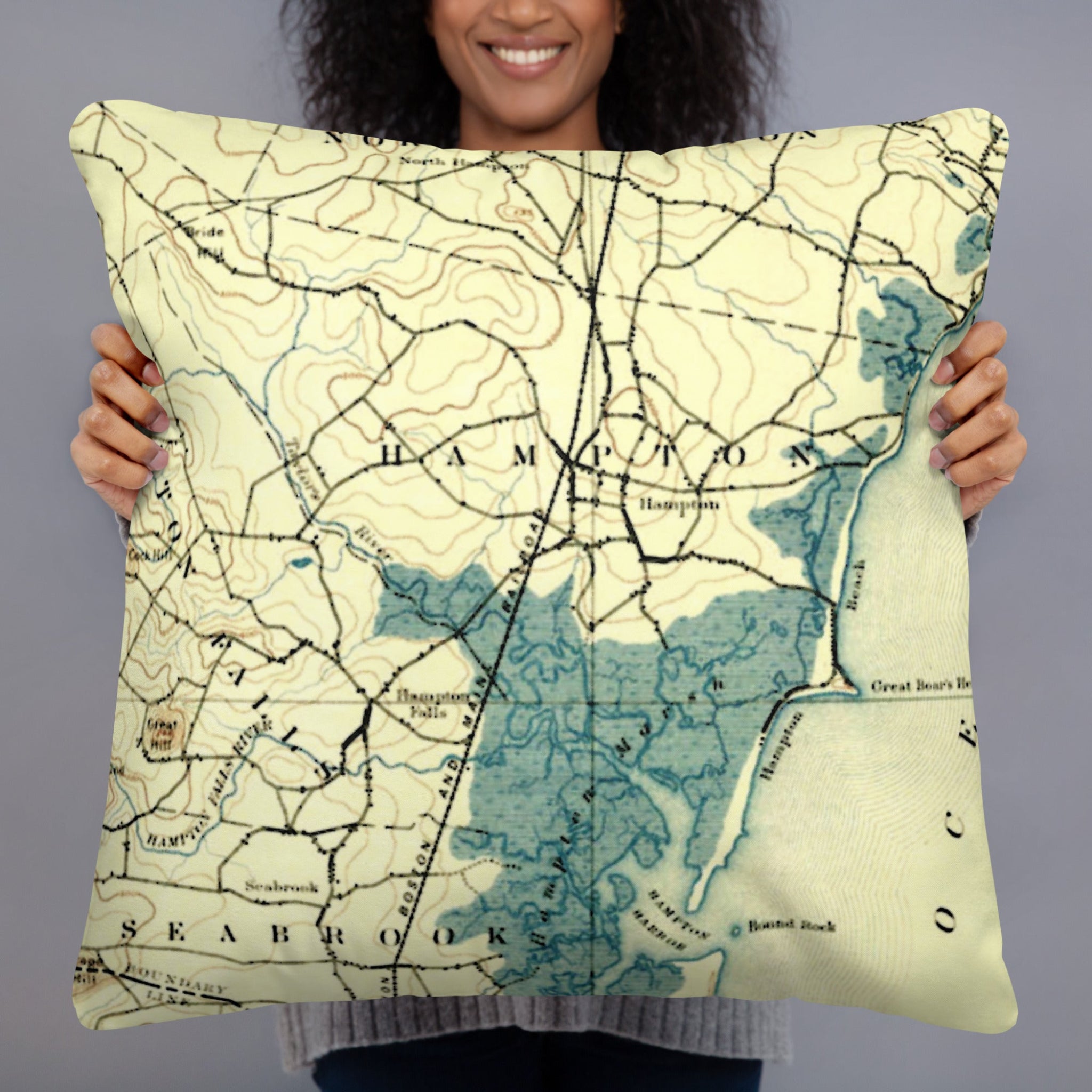 Person holding a pillow with a map design against a gray background