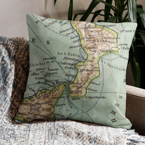 Map pillow on a textured blanket with a plant in the background