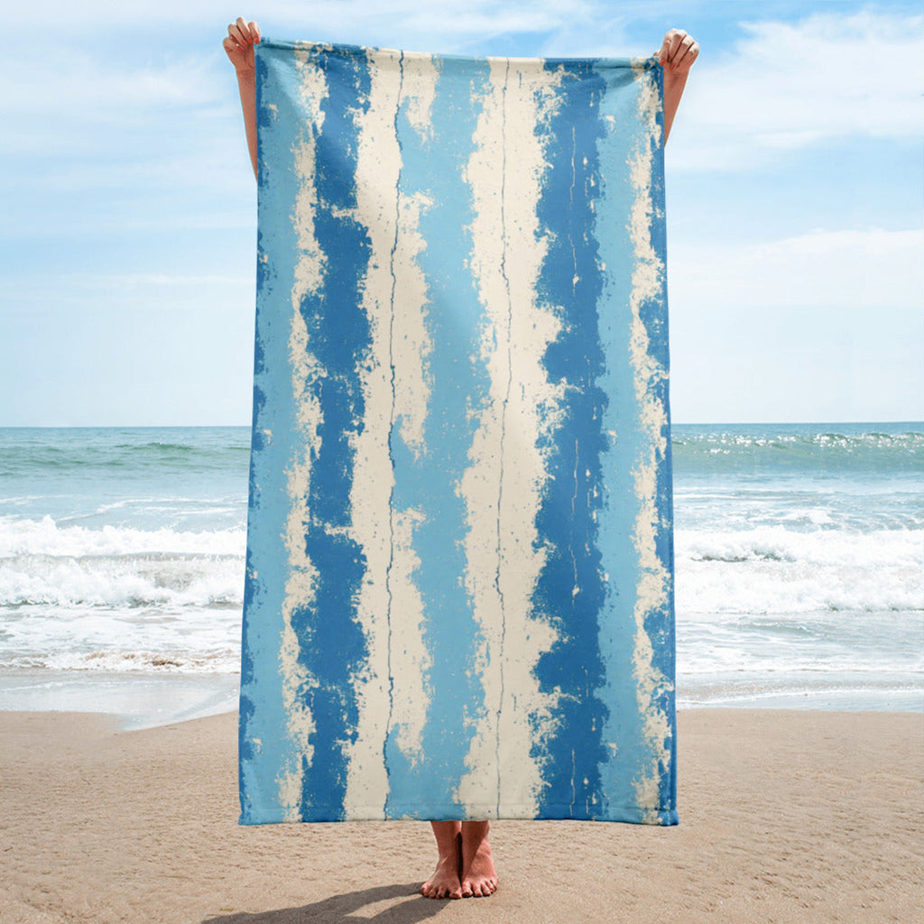 Person holding a blue and white striped towel on a beach with ocean in the background