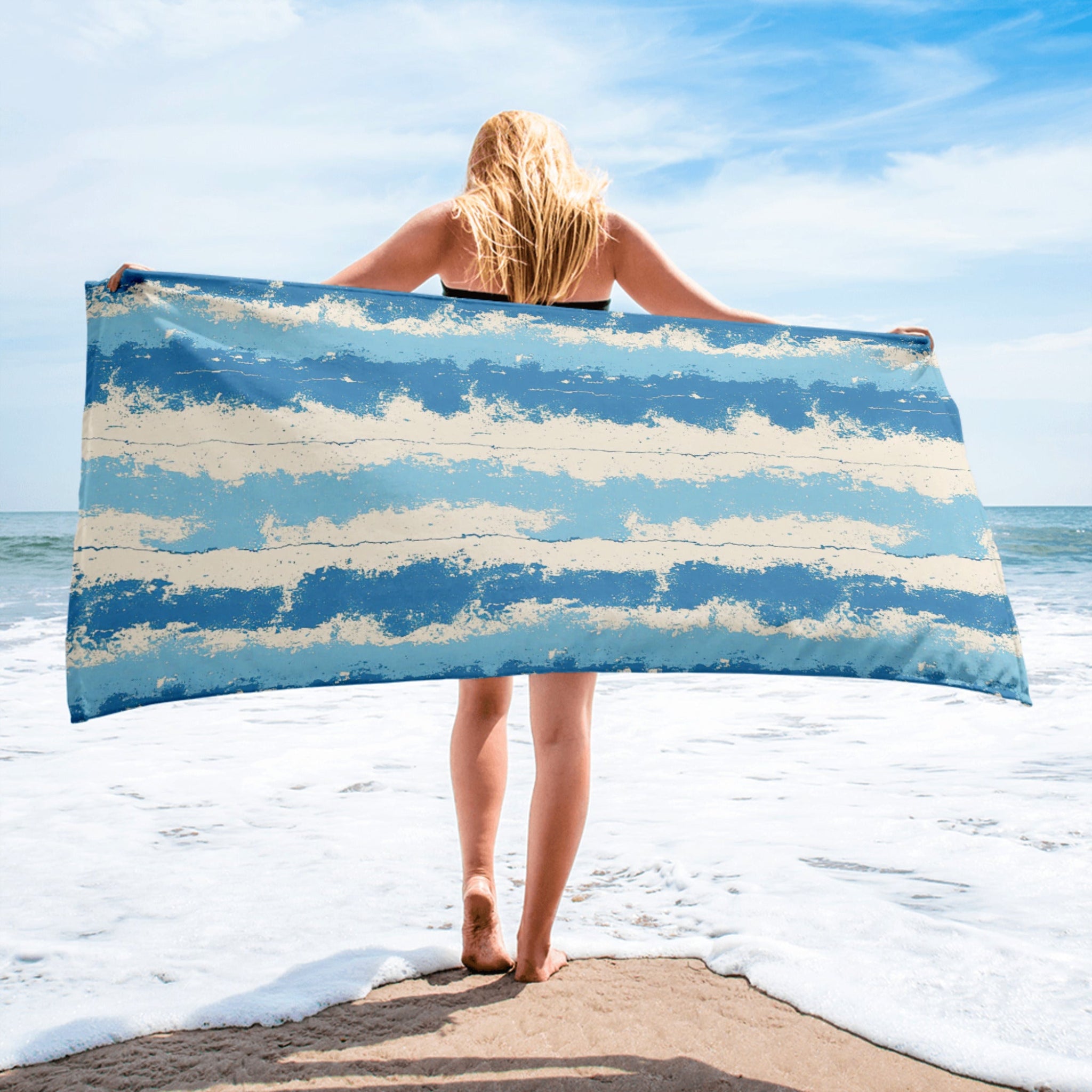 Person holding a blue and white striped towel on a beach
