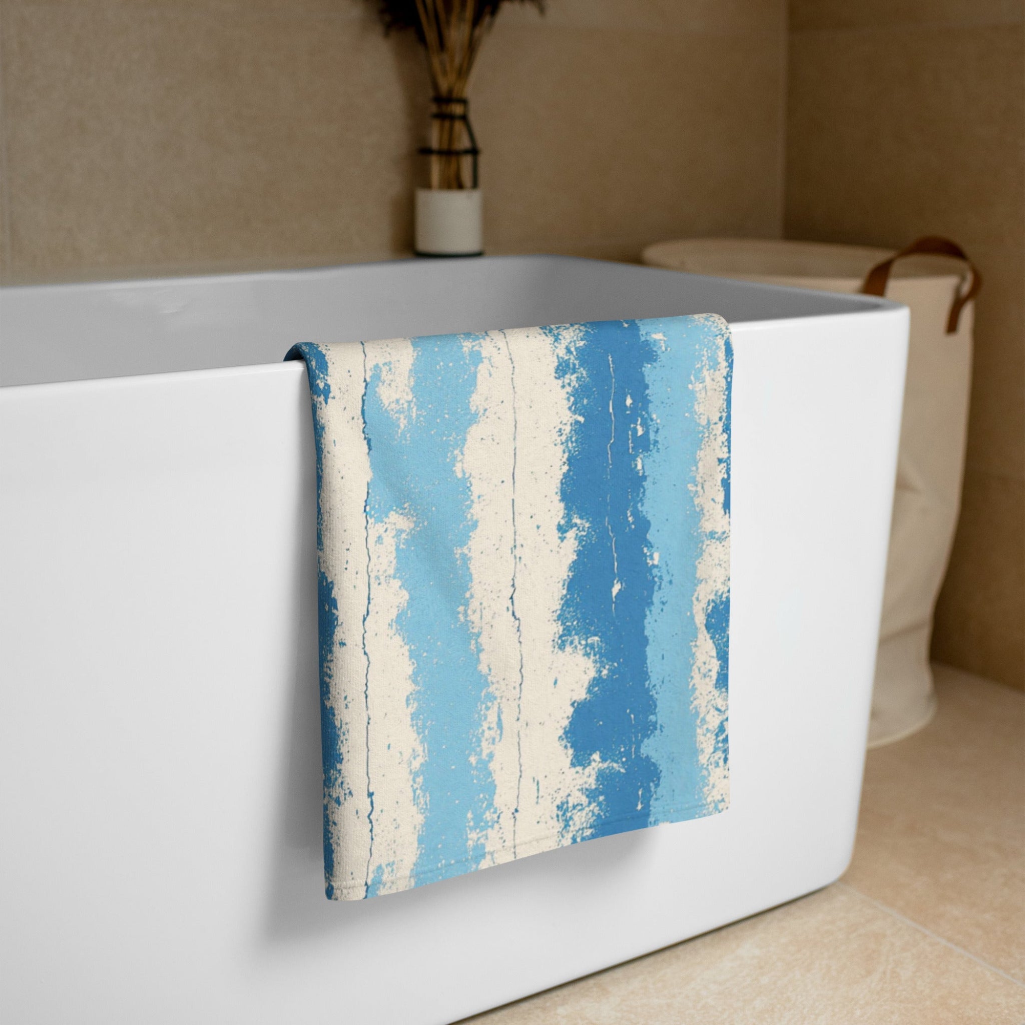 Blue and beige striped towel draped over a white bathtub in a bathroom setting.