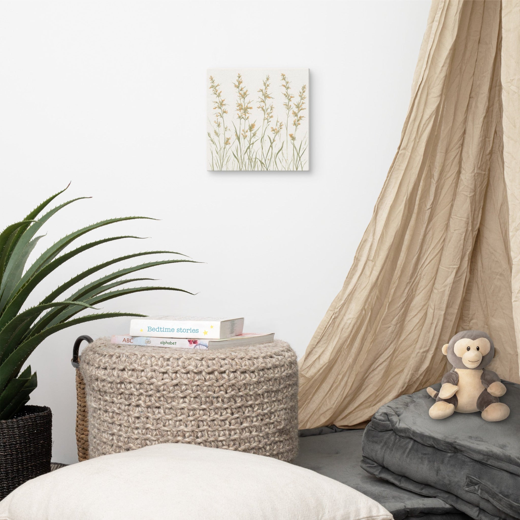 A square canvas print featuring minimalist illustrations of delicate, neutral-toned meadow grasses and wildflower stems on a cream background hanging on a wall in a room with furniture.