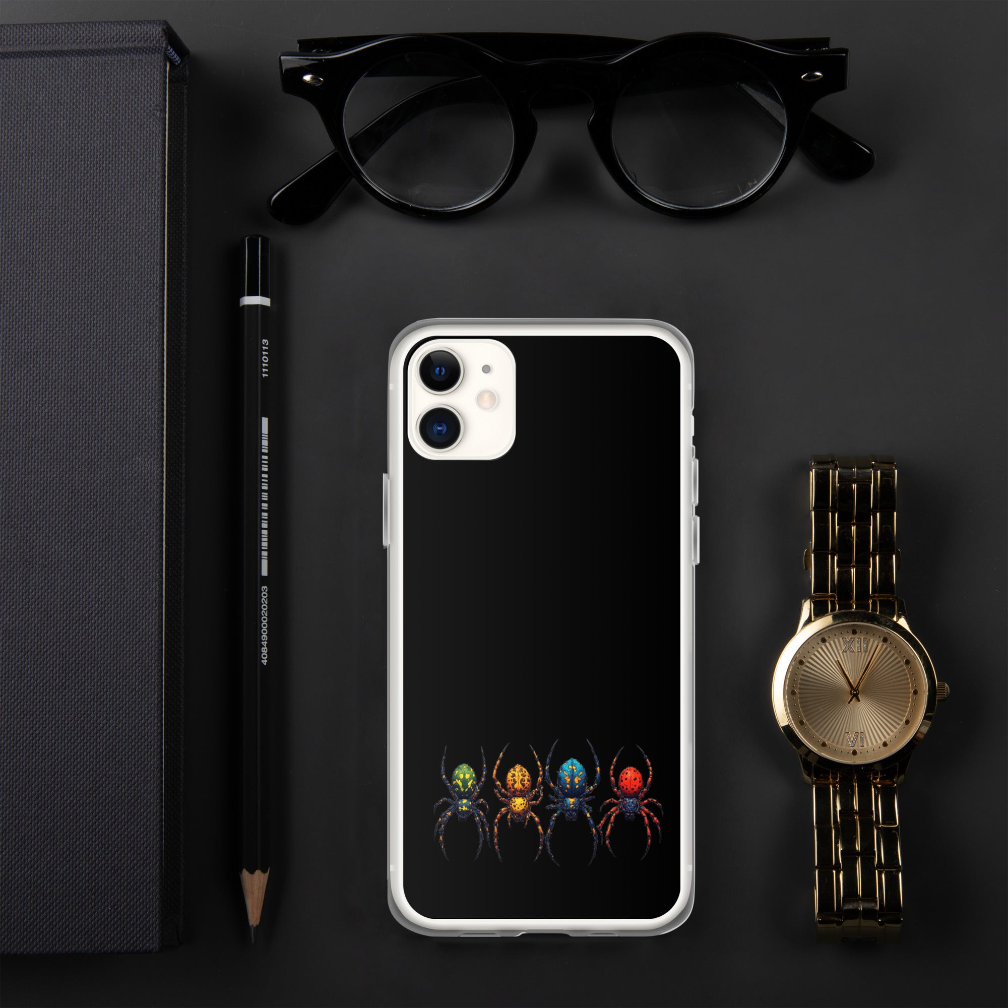 Iphone case with a color spider design laying on black desk with a pen watch a eye glasses laying next to the Iphone.
