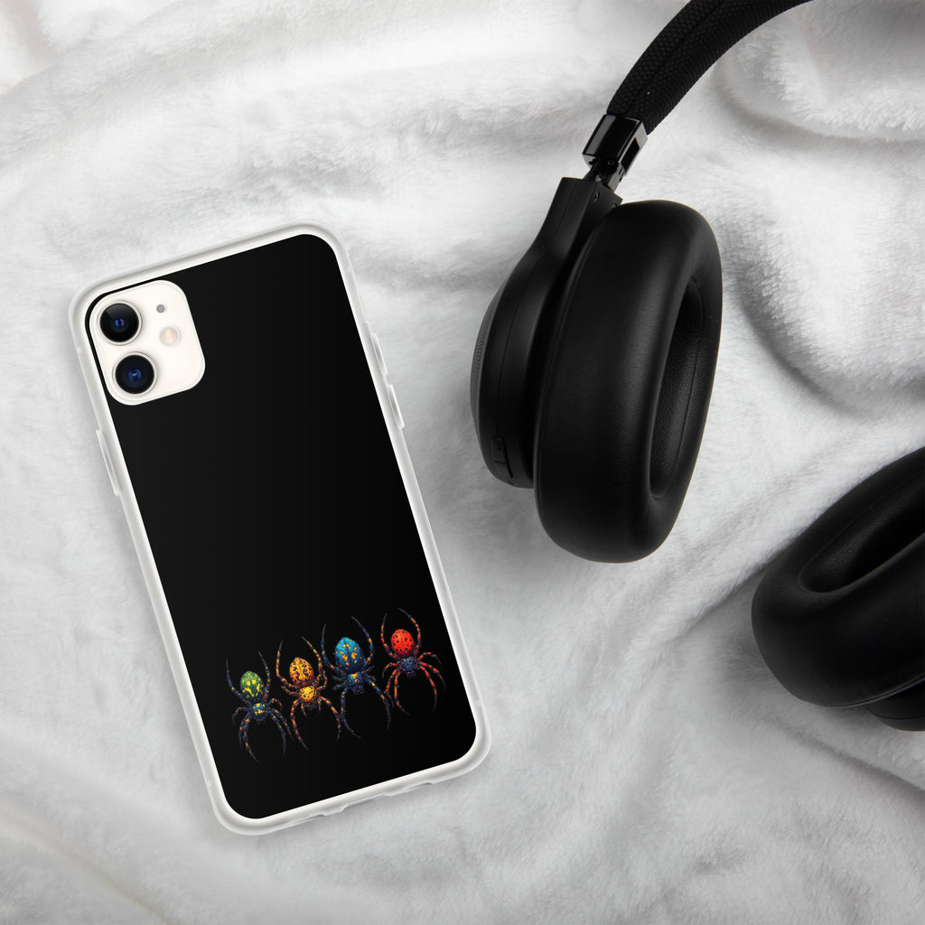A clear-edged smartphone case with a black back panel featuring four colorful spiders in green, yellow, blue, and red, styled on a white textured blanket next to black headphones.