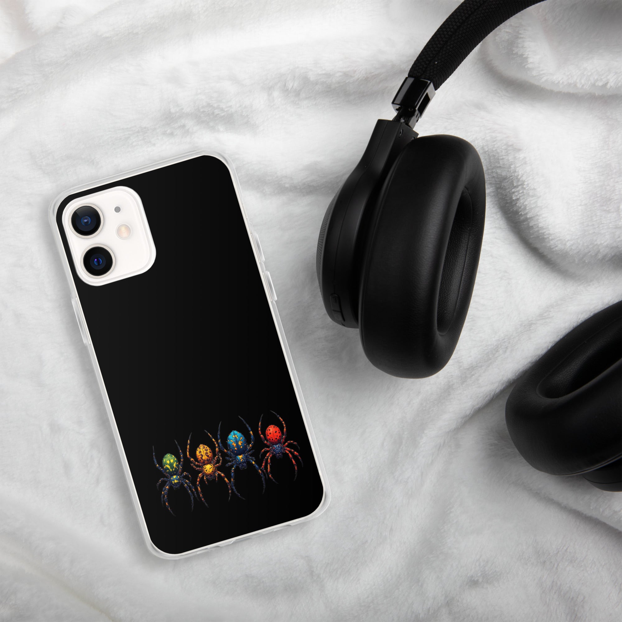 A black phone case with a colorful spider graphic, shown on a smartphone next to black headphones on a white textured blanket.