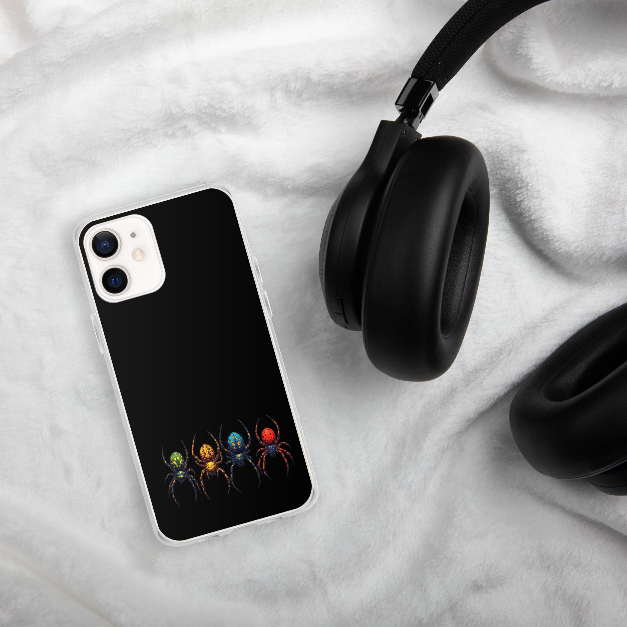 Iphone case with a color spider design laying on a white towel next to black headphones.