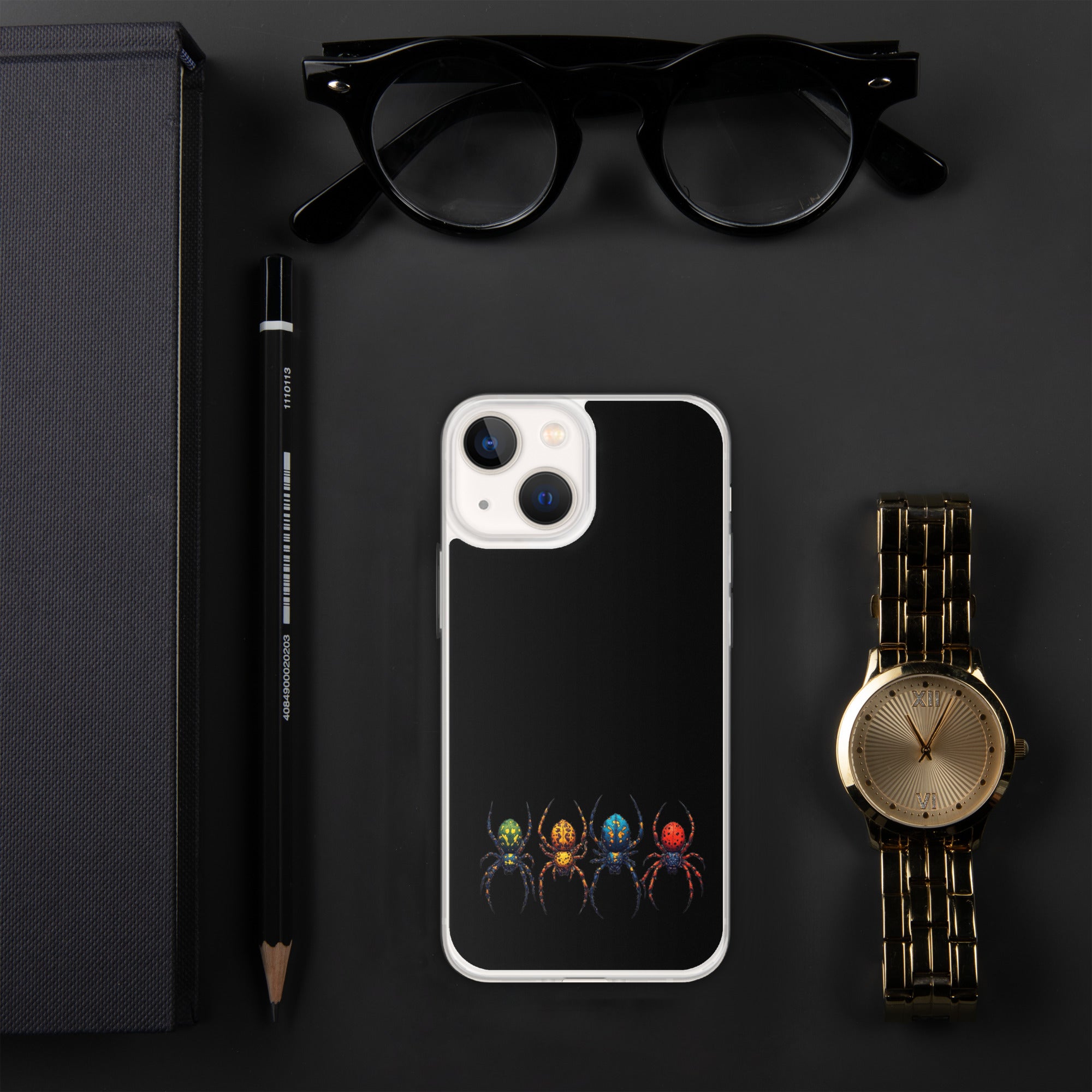 A black phone case with a colorful spider graphic, styled in a flat-lay arrangement on a dark gray background alongside black eyeglasses, a black pencil, a gold watch, and a black textured box.
