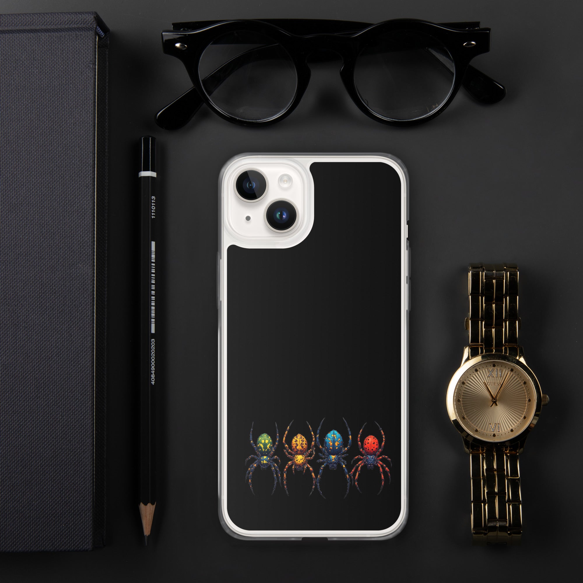 A black phone case with a colorful spider graphic, styled in a flat-lay arrangement with black eyeglasses, a black pencil, a dark textured box, and a gold watch on a dark gray background.