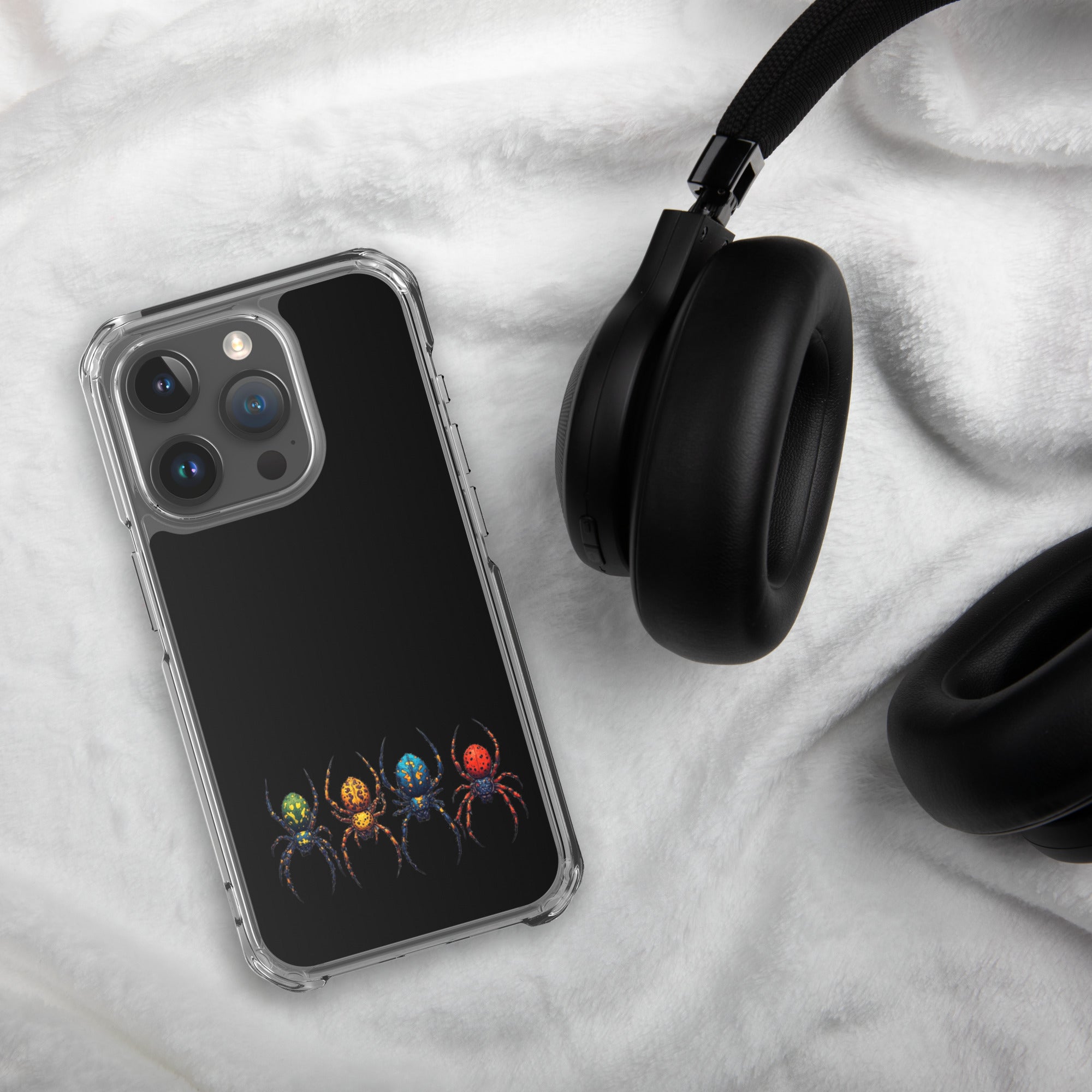 Iphone case with a color spider design laying on white textured background next to a pair of black headphones.