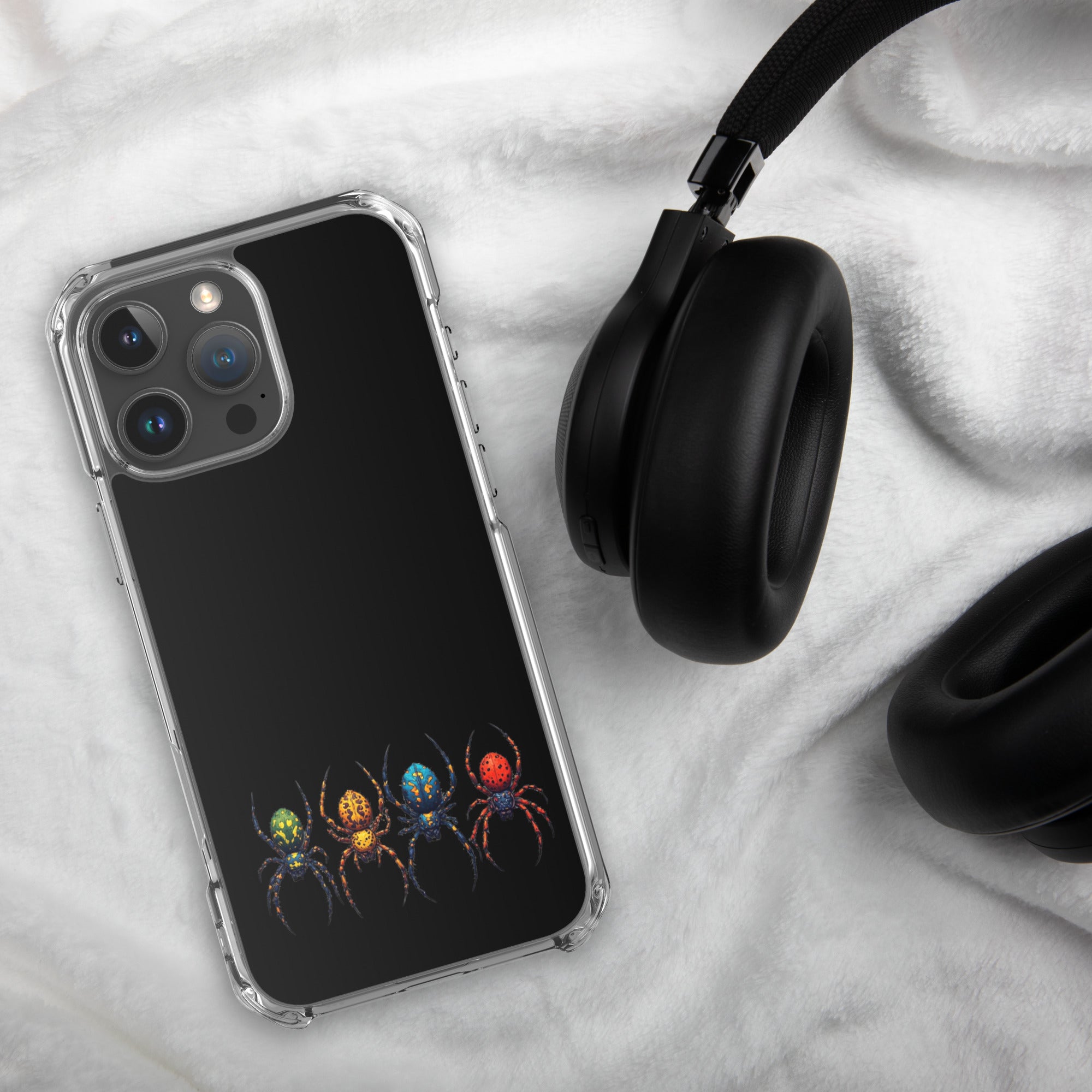 Phone case with colorful spider pattern on black background next to black headphones on white fabric