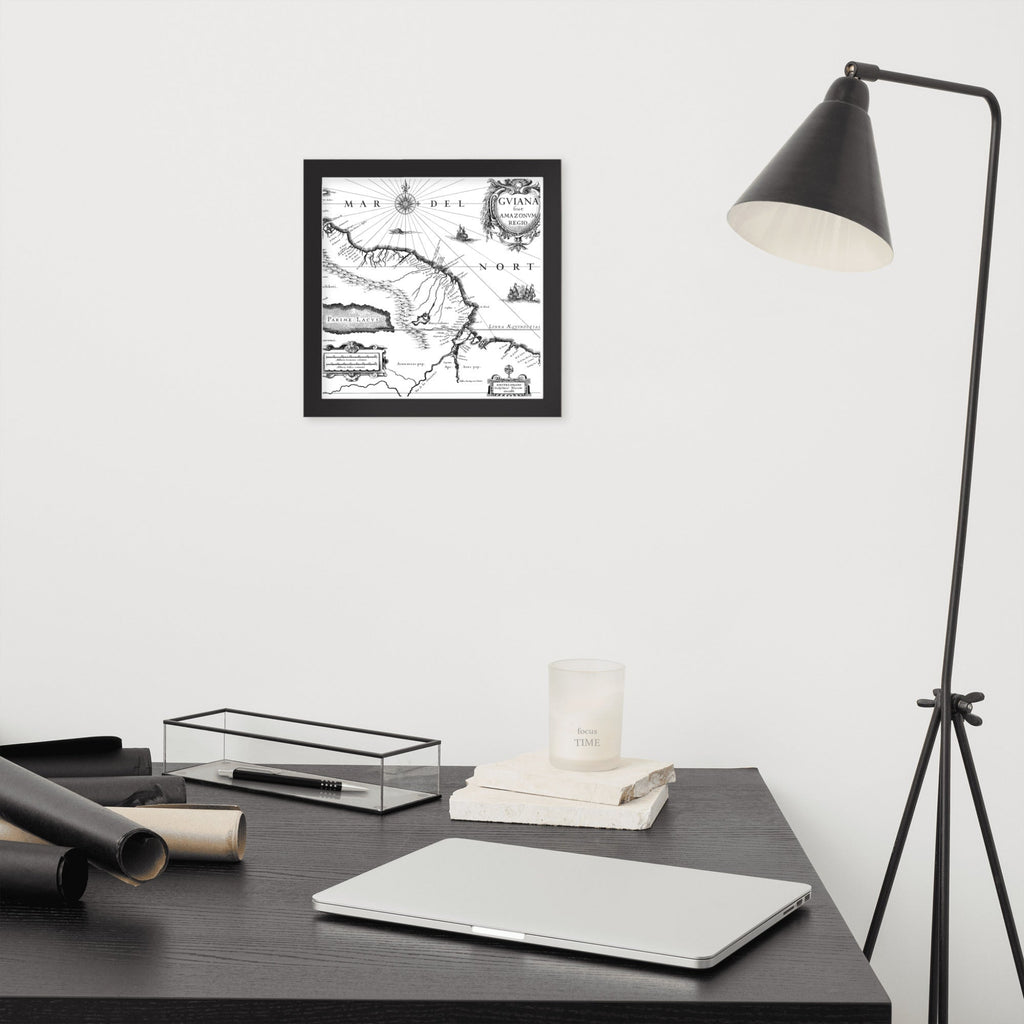 Framed black and white map on a wall above a desk with a laptop and lamp.