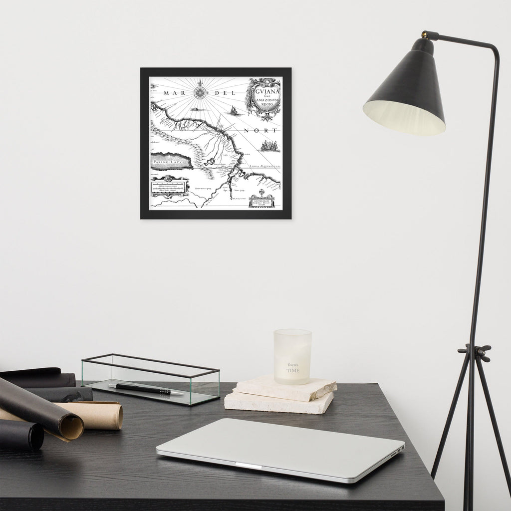 Framed map on a wall above a desk with a laptop and lamp.