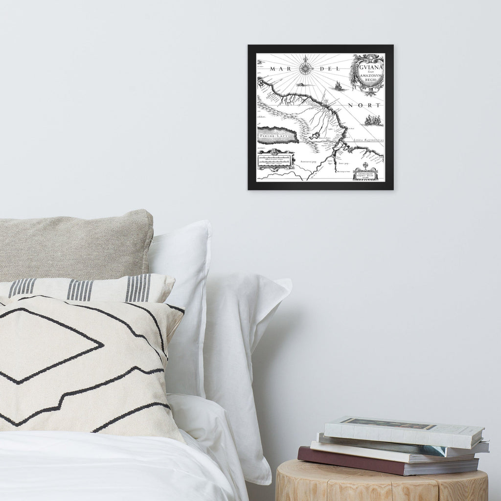 Framed map on a wall above a bed with pillows and books.