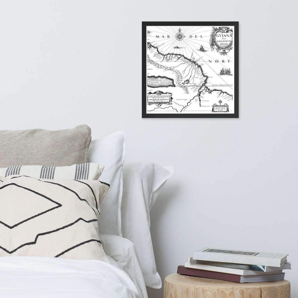 Framed map on a wall above a bed with books on a side table.