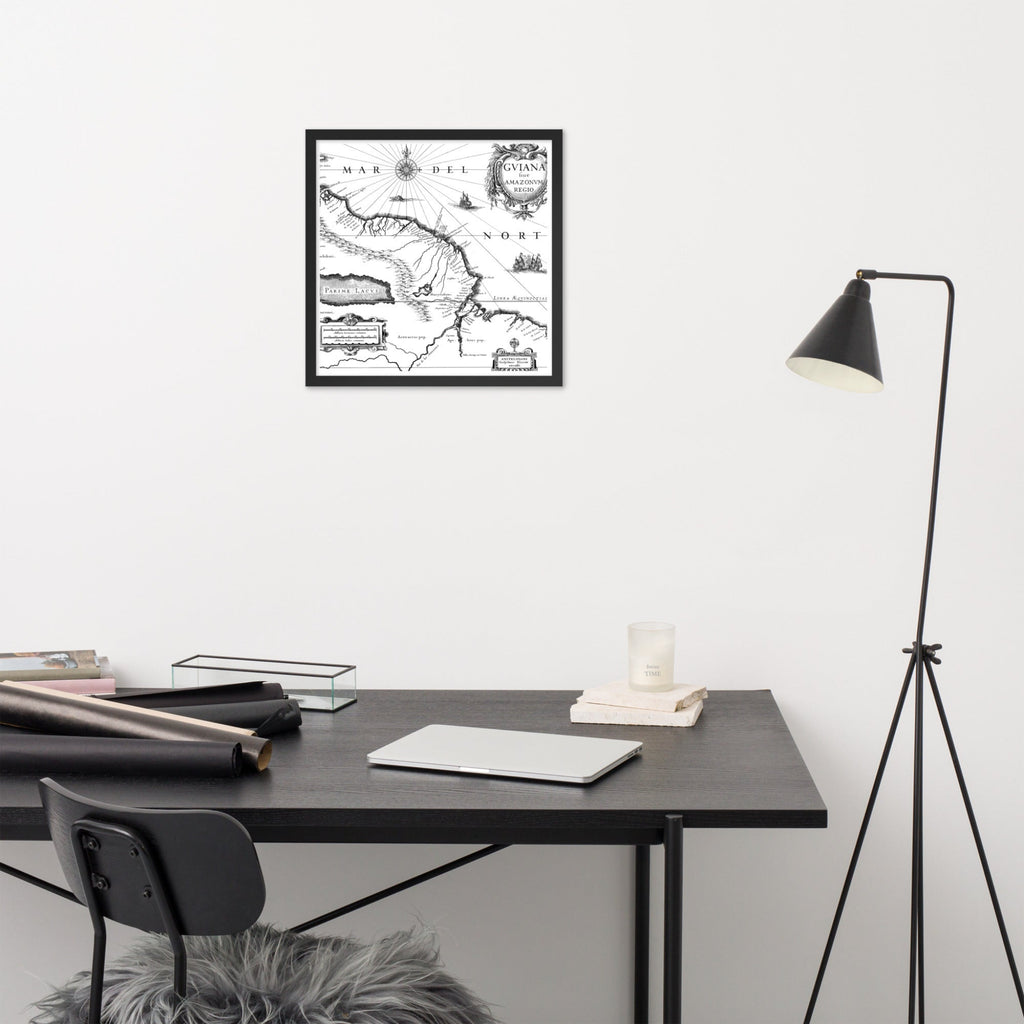 Framed map on a wall above a desk with a lamp and chair.