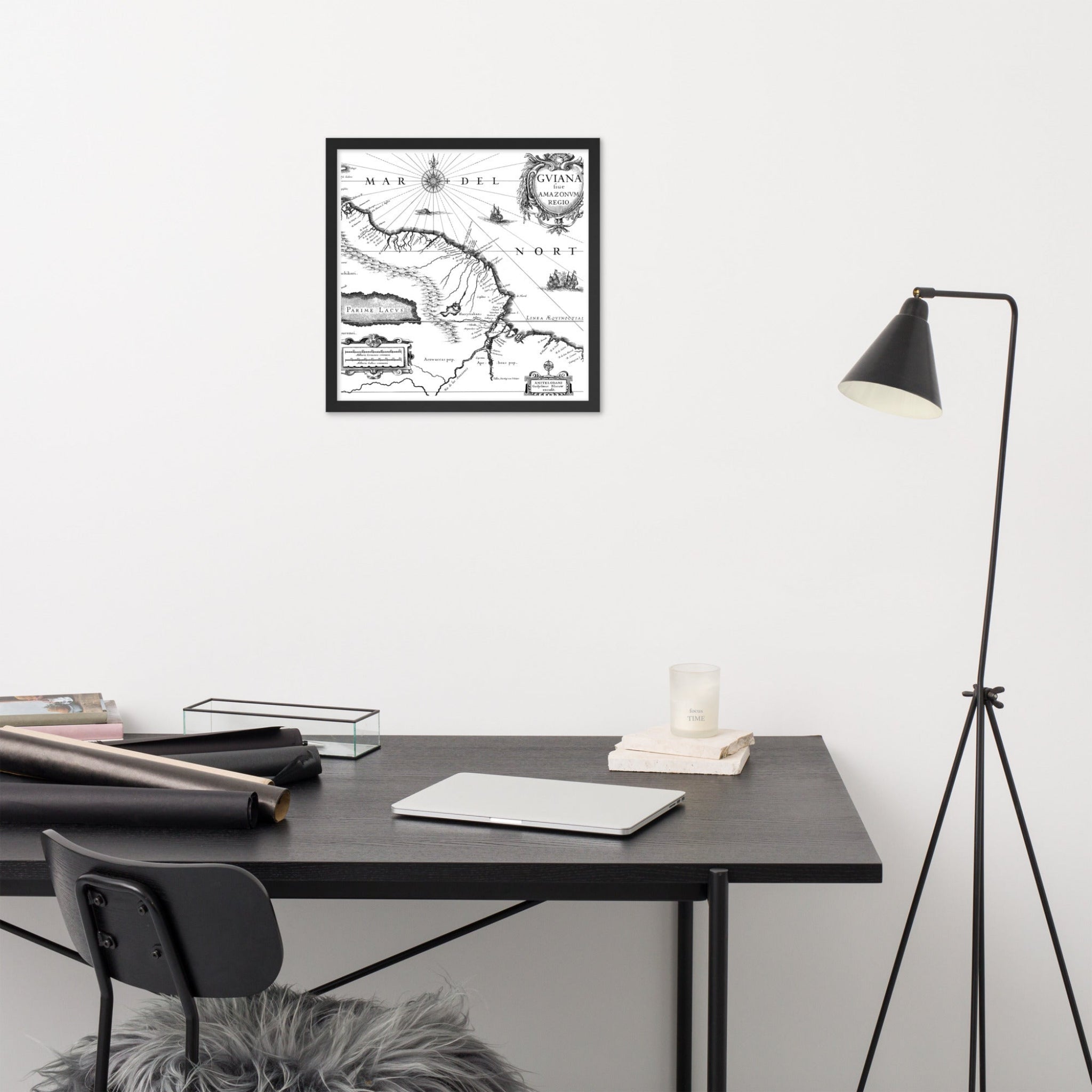 Framed map on a wall above a desk with a lamp and chair.