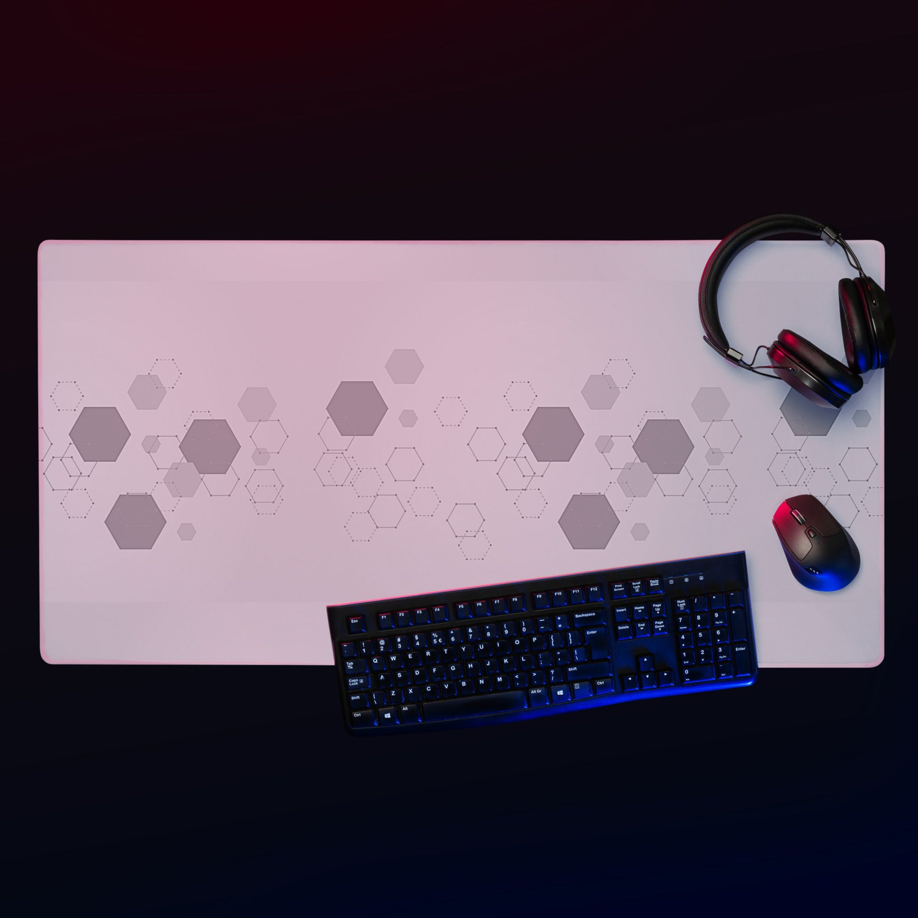 Desk setup with a large mouse pad, keyboard, mouse, and headphones on a dark background. 