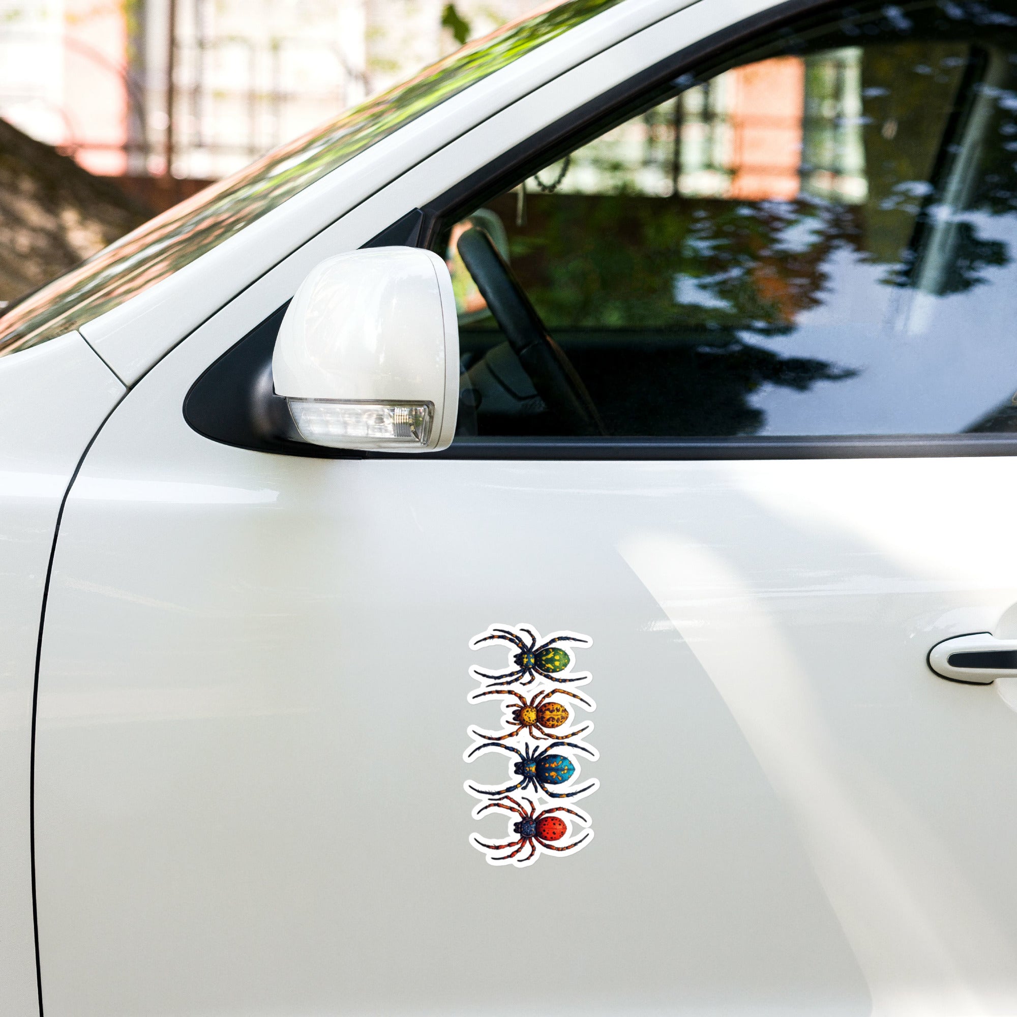 The outside of a white car door with a vinyl decal of colorful spiders.