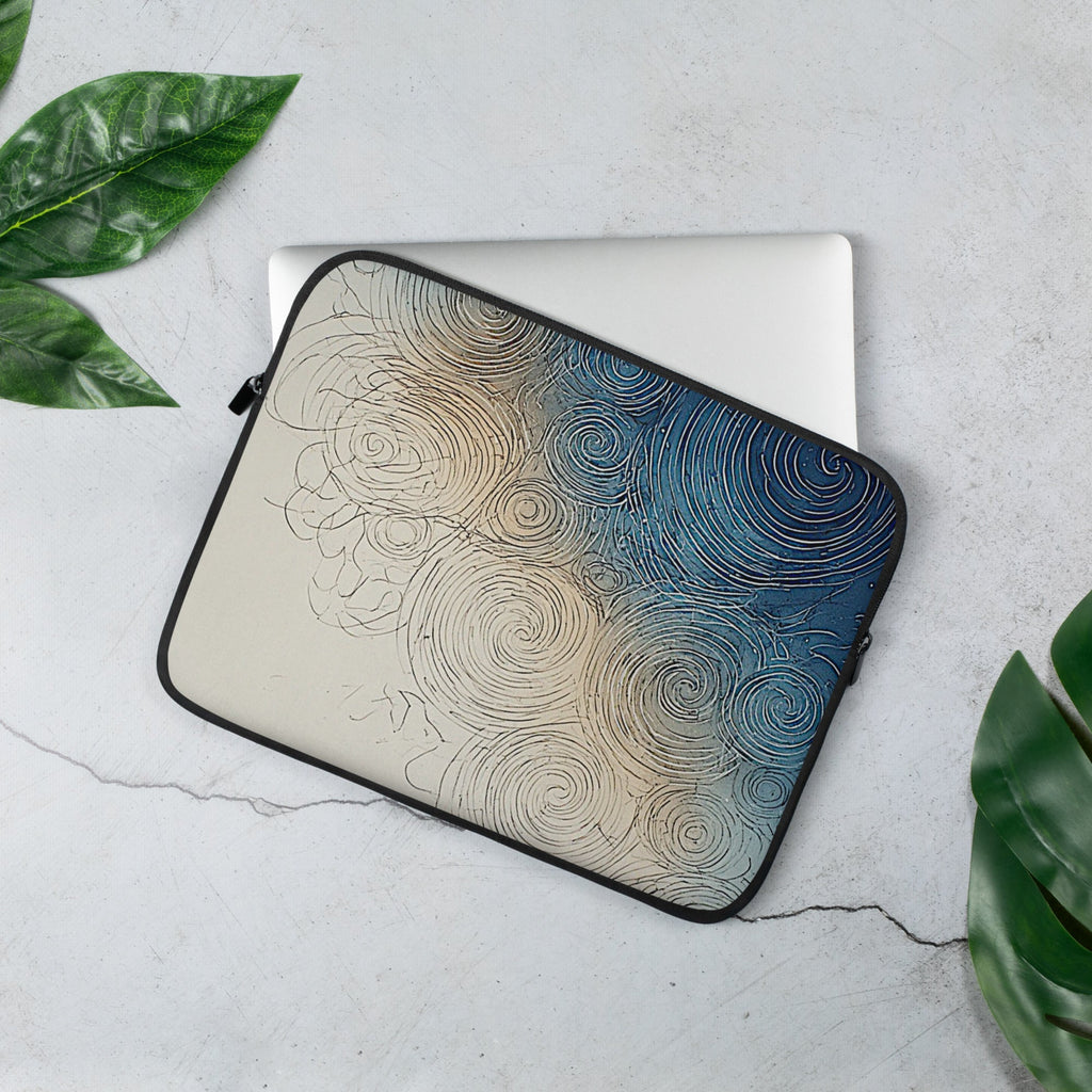 A laptop sleeve with a swirling abstract pattern in beige and blue, shown on top of a silver laptop on a light gray surface with green leaves in the corners.
