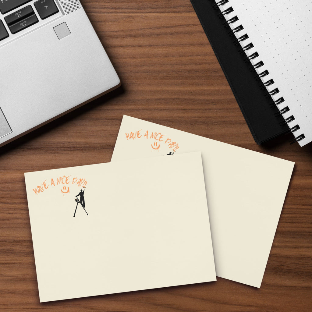 Beige extra large post it sticky note pad with black silhouette and text 'Have a nice day' on a wood desk with a laptop and  spiral notebook
