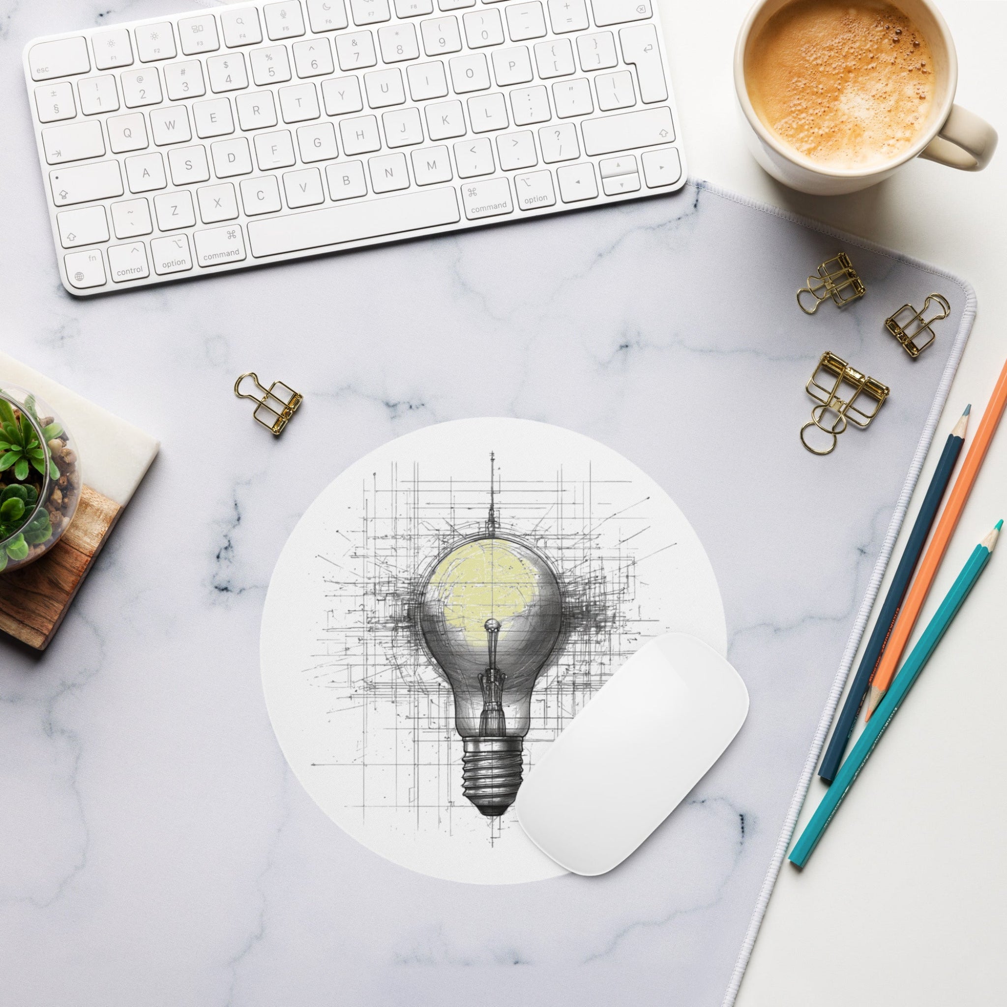 Desk setup with a light bulb mouse pad, keyboard, coffee, and office supplies on a marble surface.