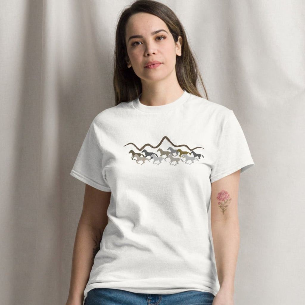 Woman wearing a white graphic t-shirt featuring a wild mustang stampede and mountain design, styled casually for a western boho look. 