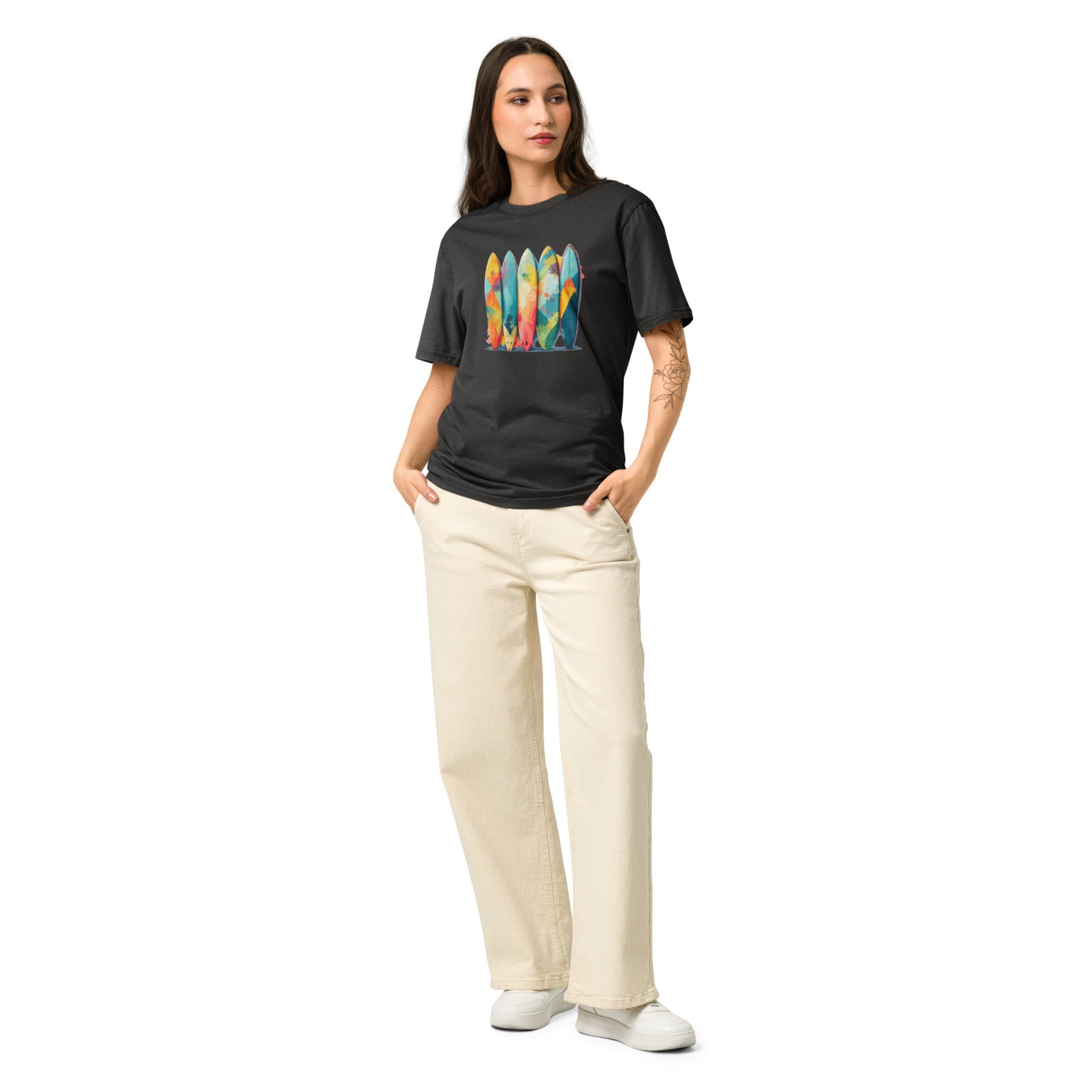 A woman wearing crewneck t-shirt featuring a vibrant graphic print of five upright surfboards decorated with colorful abstract geometric patterns.