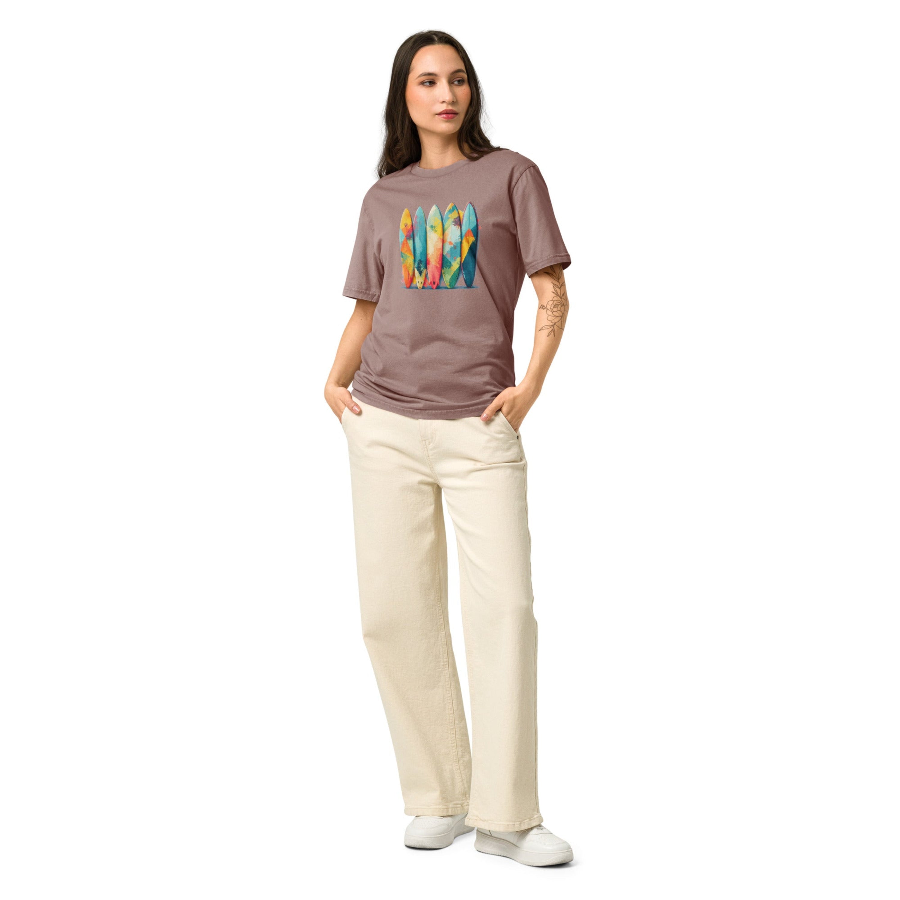 A woman wearing crewneck t-shirt featuring a vibrant graphic print of five upright surfboards decorated with colorful abstract geometric patterns.