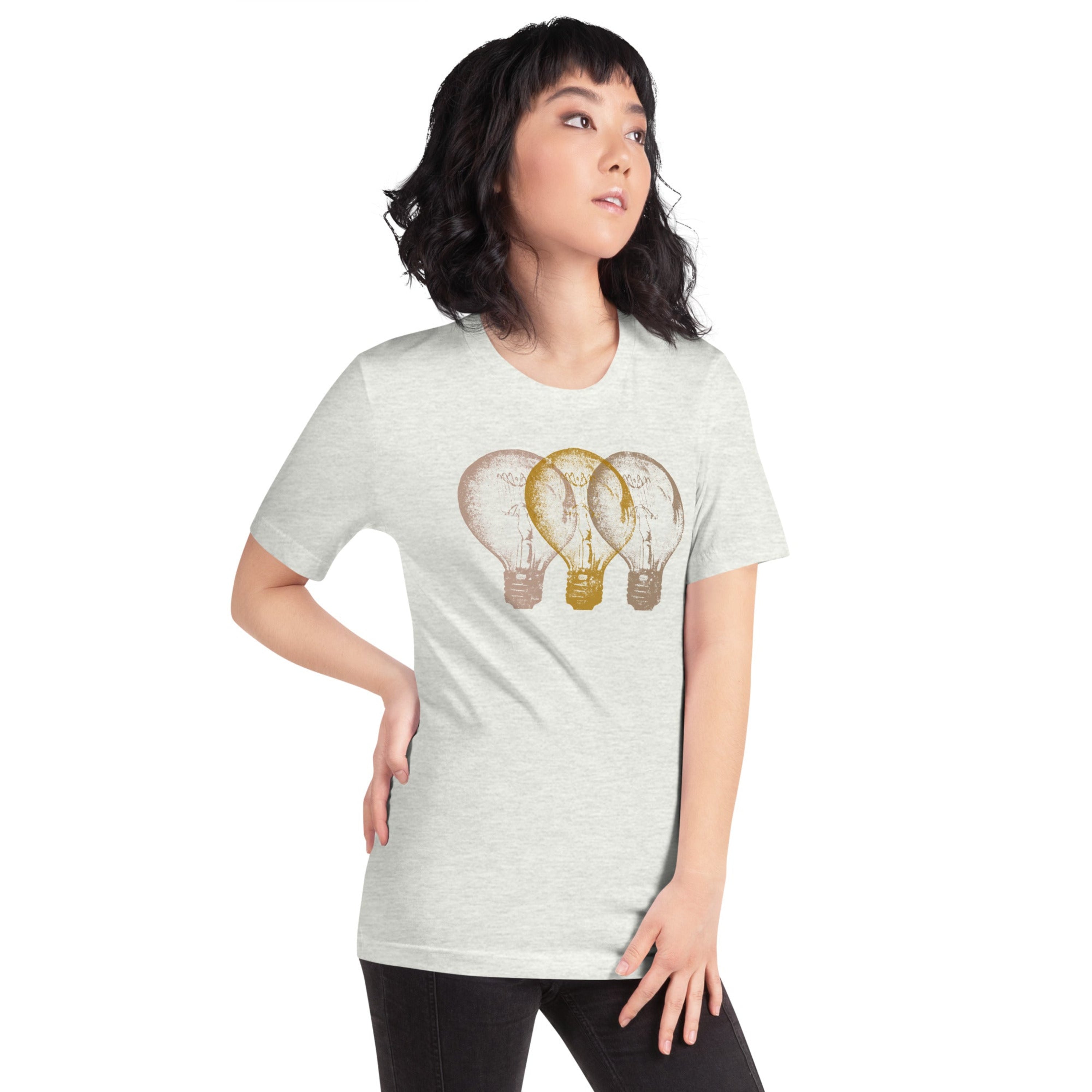 Woman wearing a light grey t-shirt with an Edison light bulb graphic design, standing against a white wall.