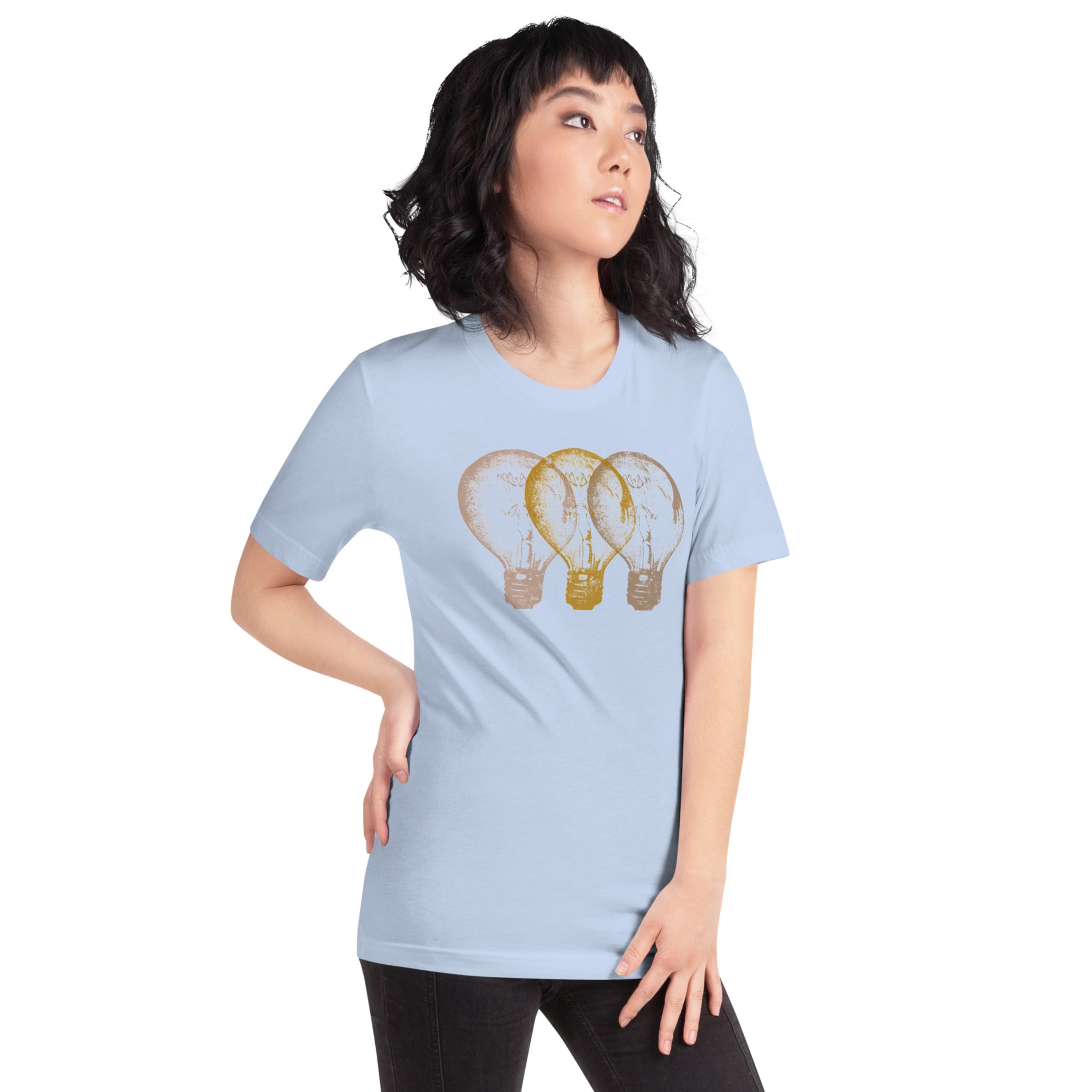 Woman wearing a light blue t-shirt with an Edison light bulb graphic design, standing against a white wall.
