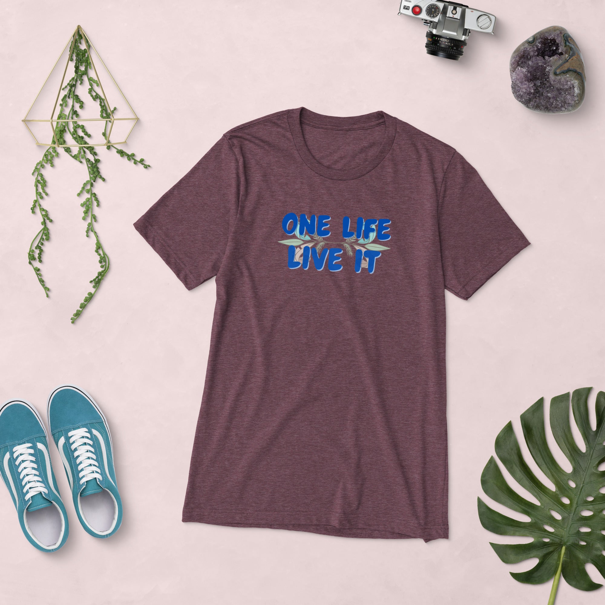 Maroon t-shirt with 'ONE LIFE LIVE IT' text on a light pink background with shoes and decor items.