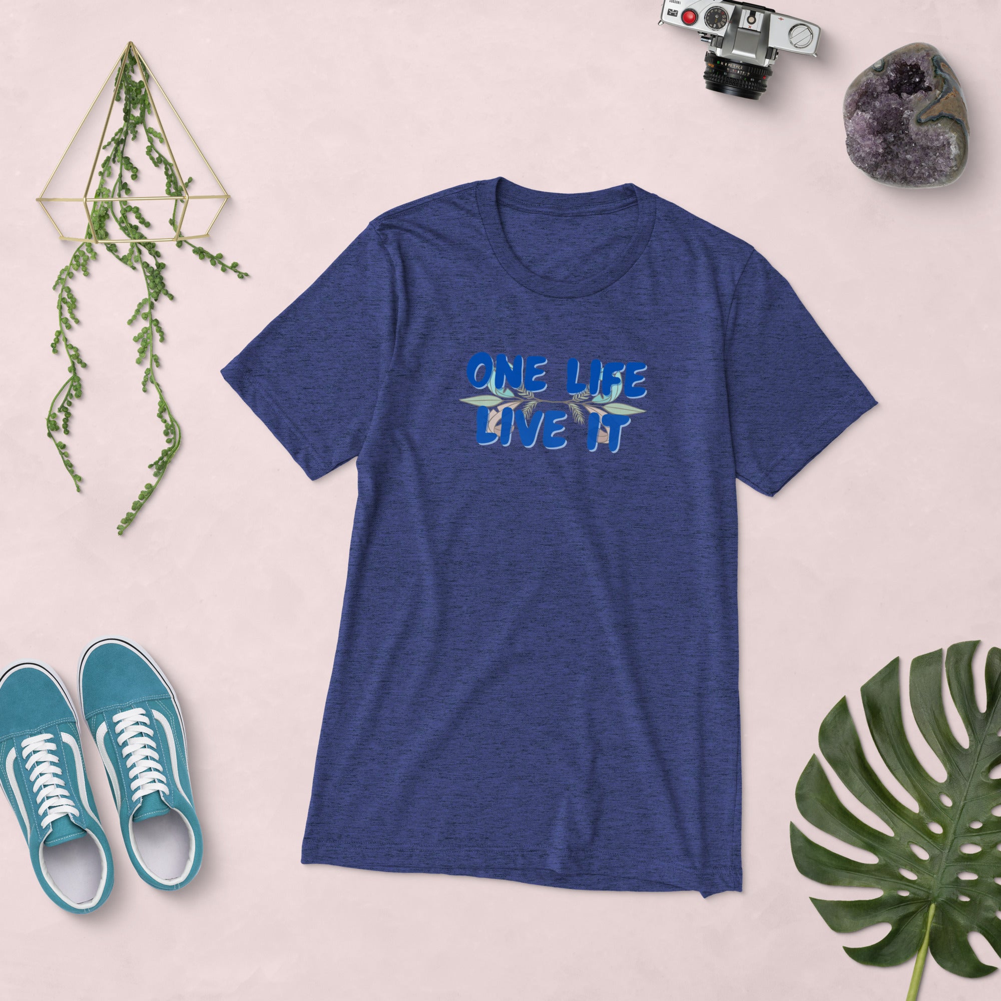 Blue t-shirt with 'ONE LIFE LIVE IT' text on a light pink background with shoes and decorative items.