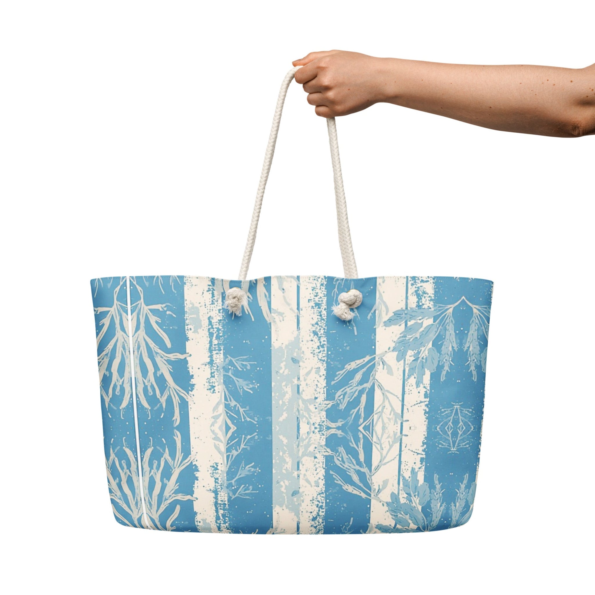 Tote bag with blue and white design held by a hand on a white background