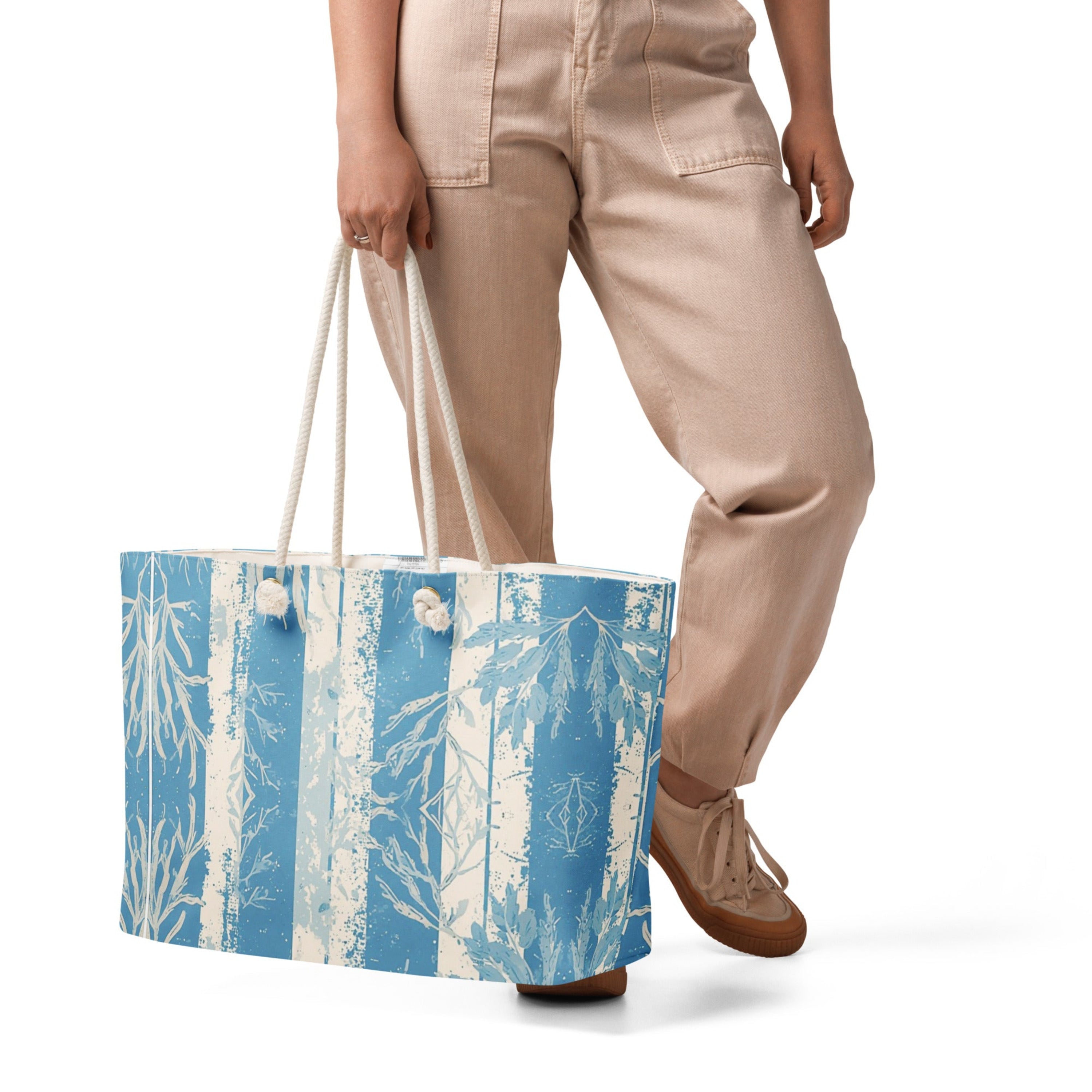 Person holding a oversized weekender bag featuring an all-over blue botanical coral print design with thick cream cotton rope handles.