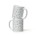Two white mugs with blue floral patterns stacked on a white background