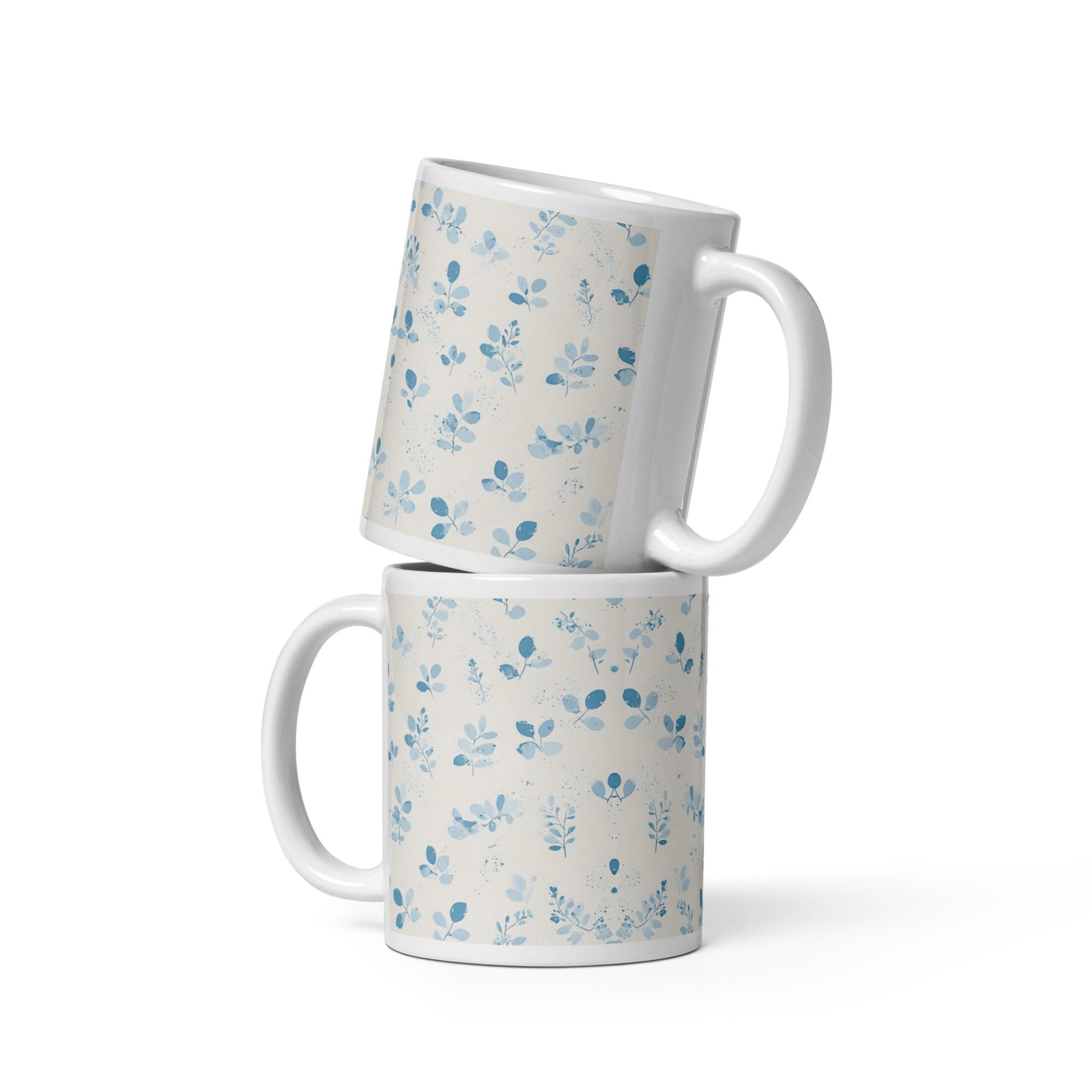 Two white mugs with blue floral patterns stacked on a white background