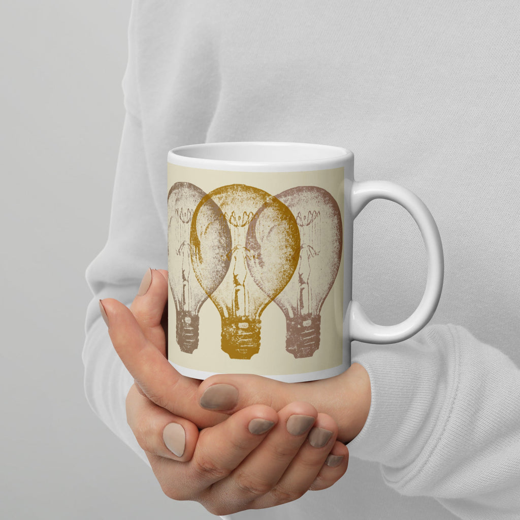 Person holding a mug with light bulb design against a gray background.