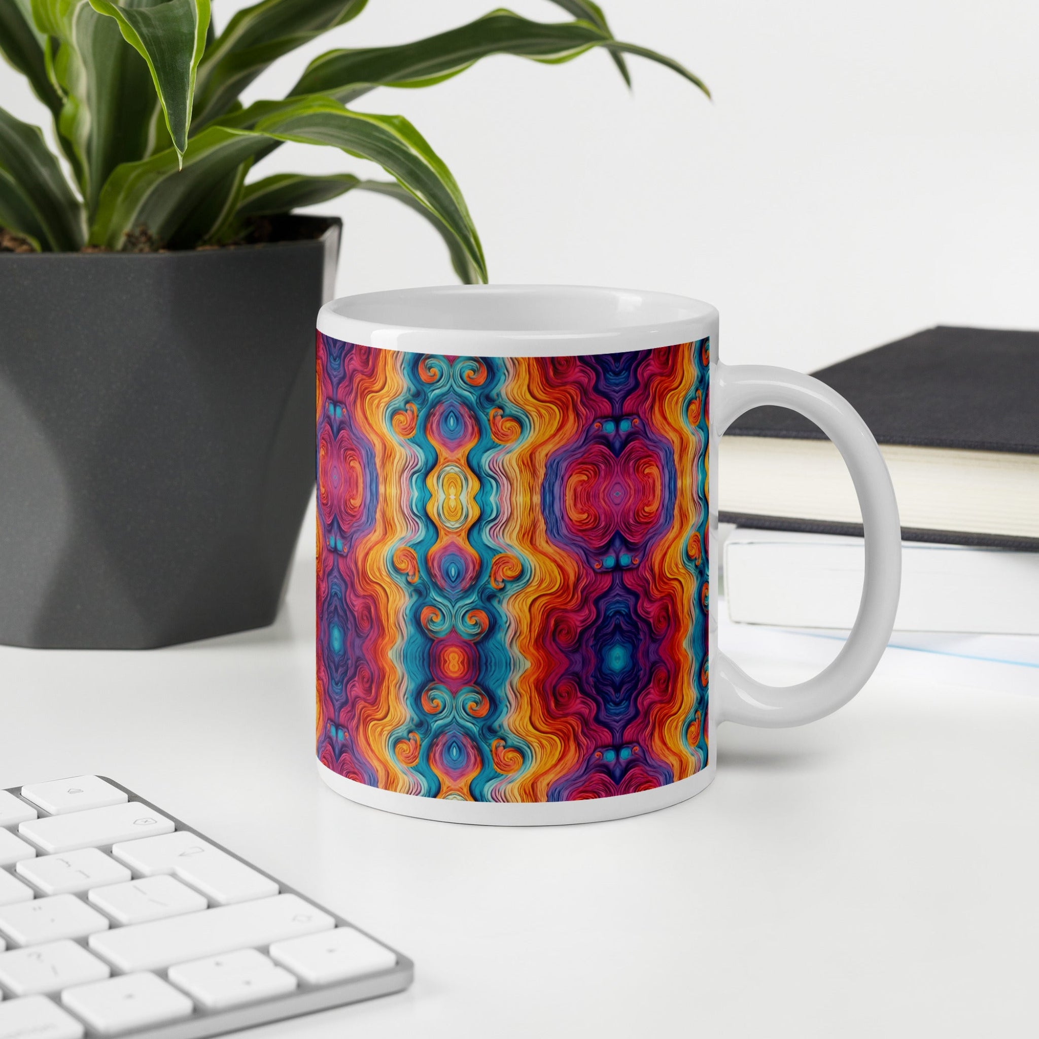 Multicolored ceramic coffee cup on white table next to a potted house plant. 