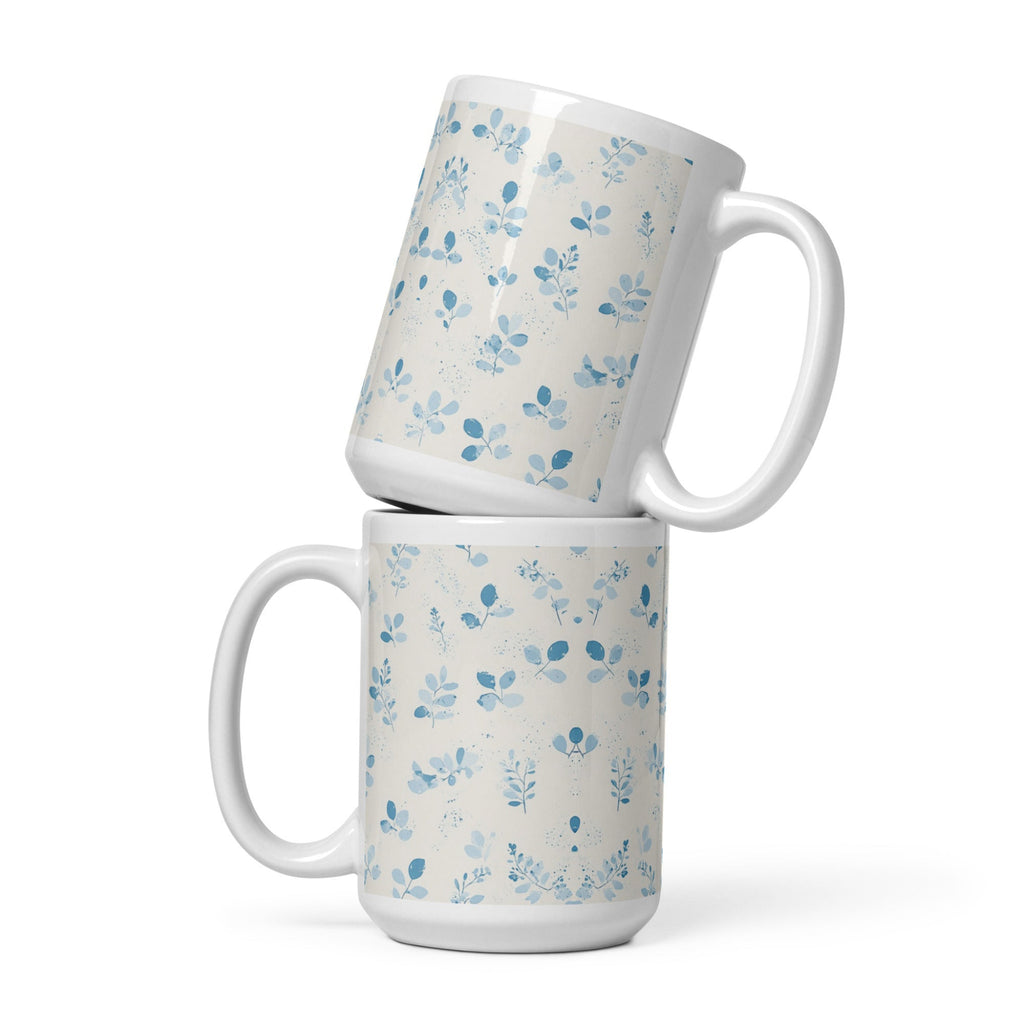 Two white mugs with blue floral patterns stacked on a white background