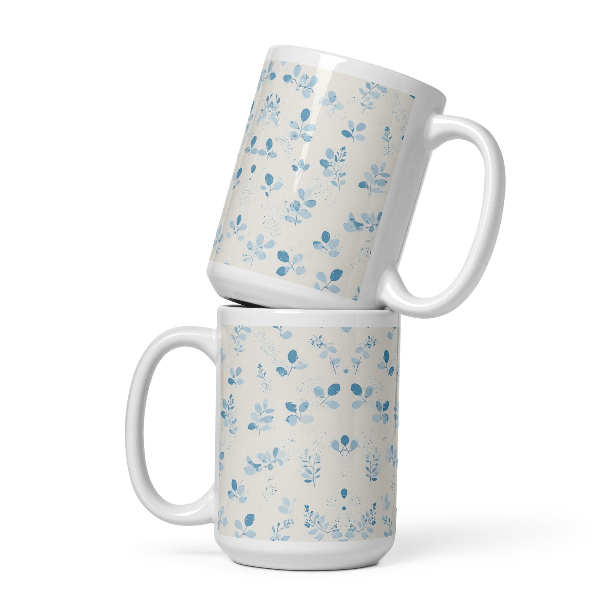 Two white mugs with blue floral patterns stacked on a white background