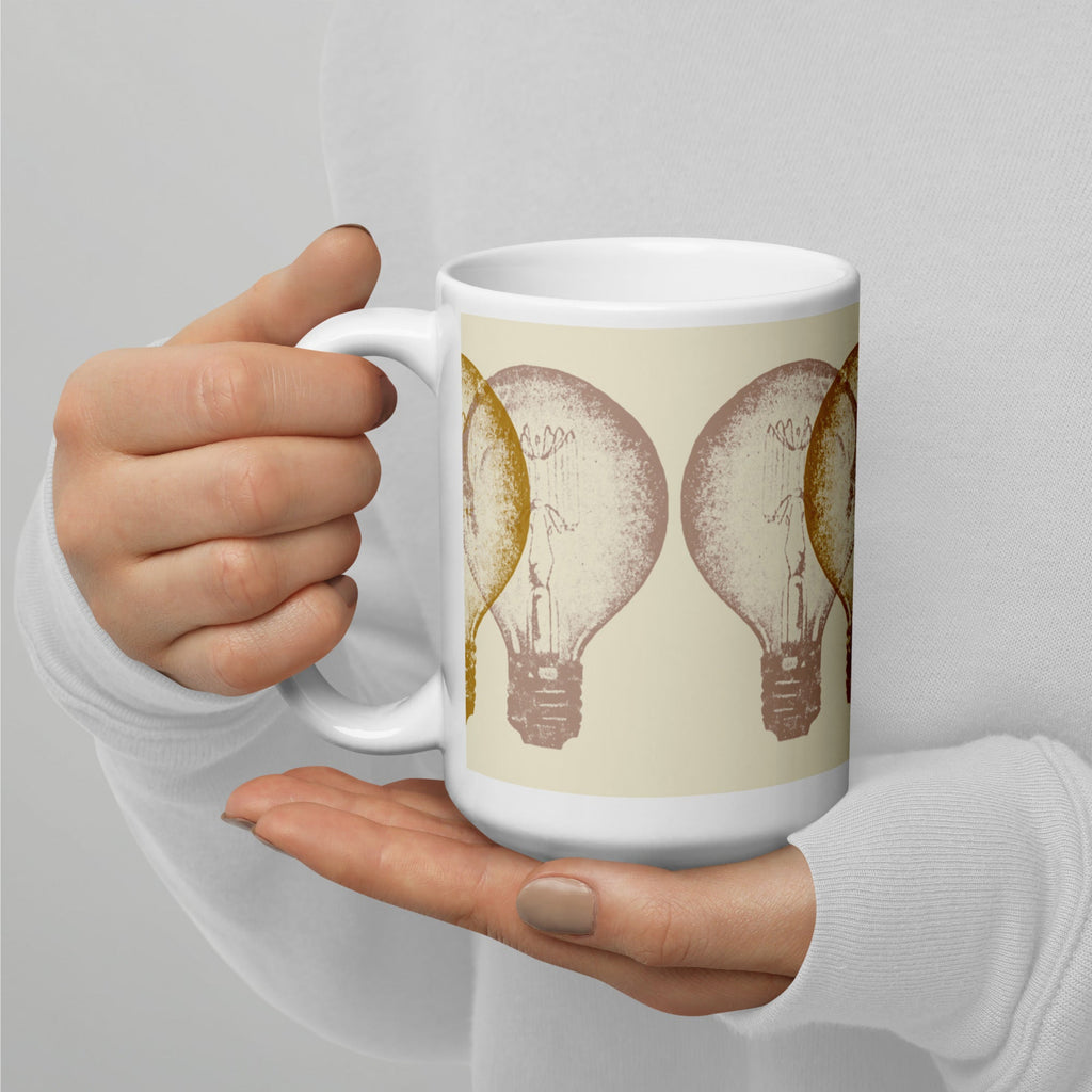 Hand holding a mug with light bulb design on a plain background.