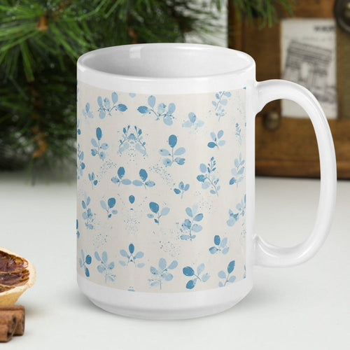 White mug with blue floral pattern on a white surface with Christmas decorations.