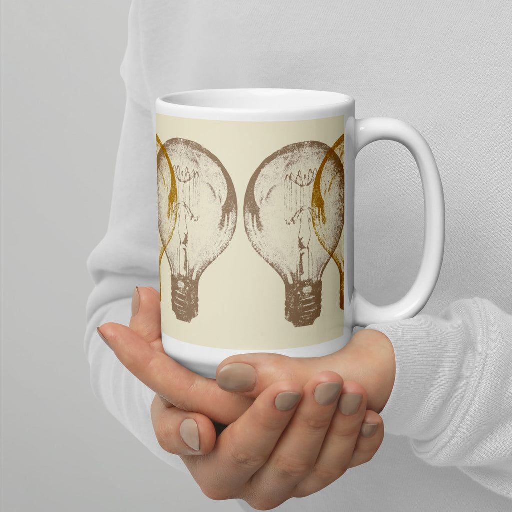 Person holding a mug with light bulb design on a plain background.