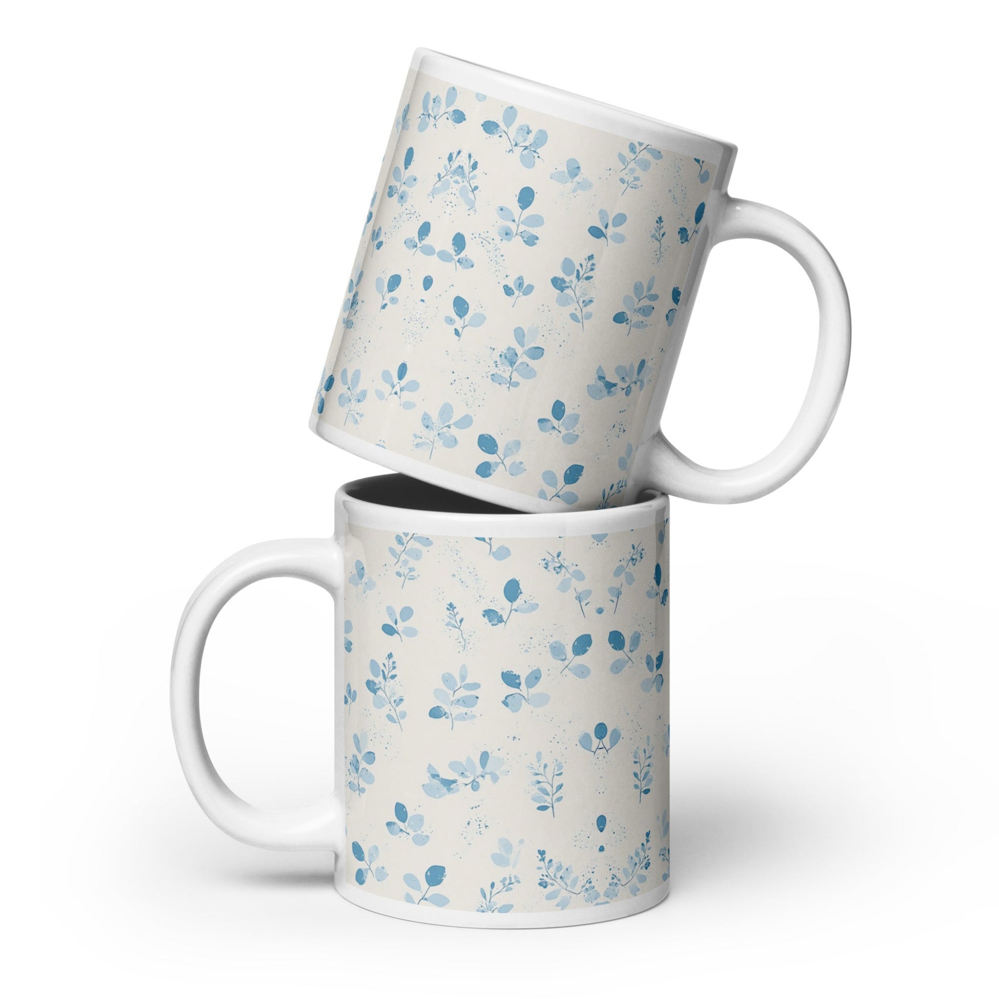 Two white mugs with blue floral patterns stacked on a white background