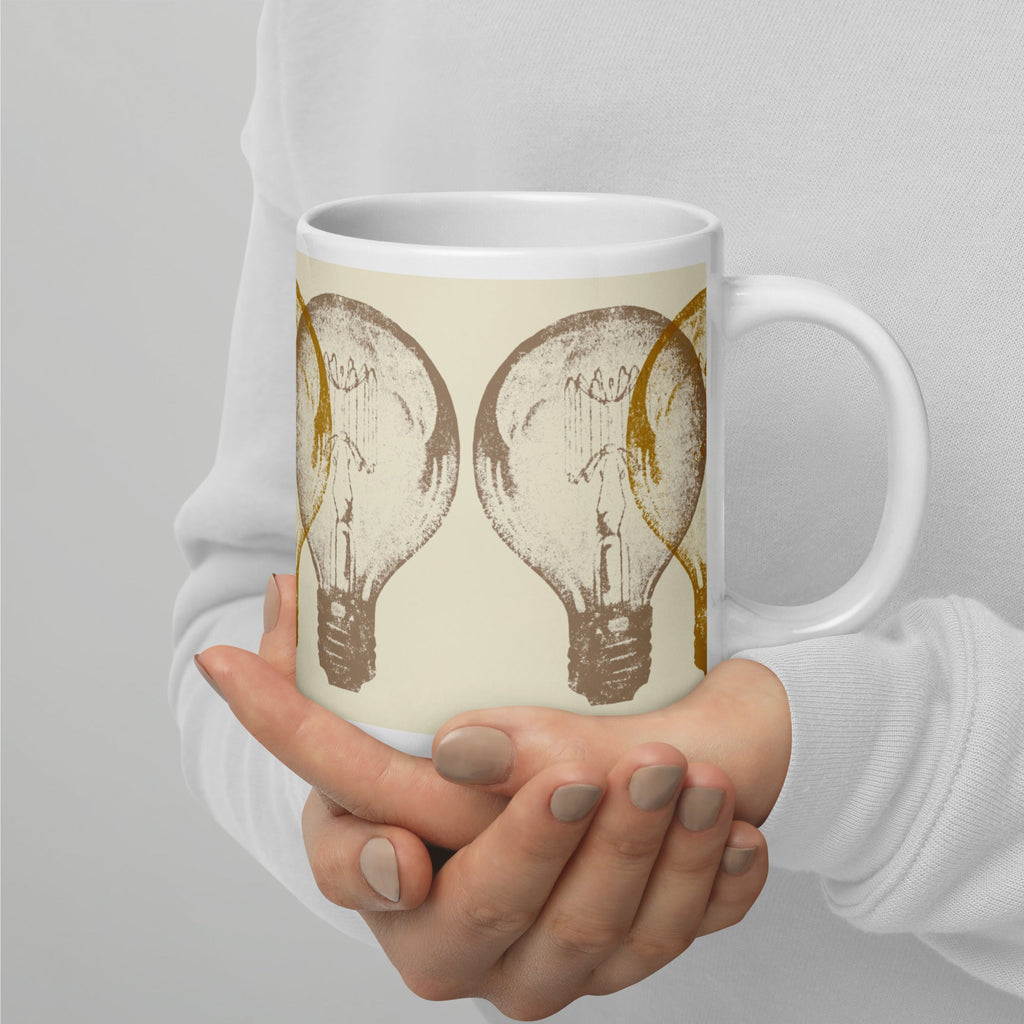 Person holding a mug with light bulb design against a gray background.