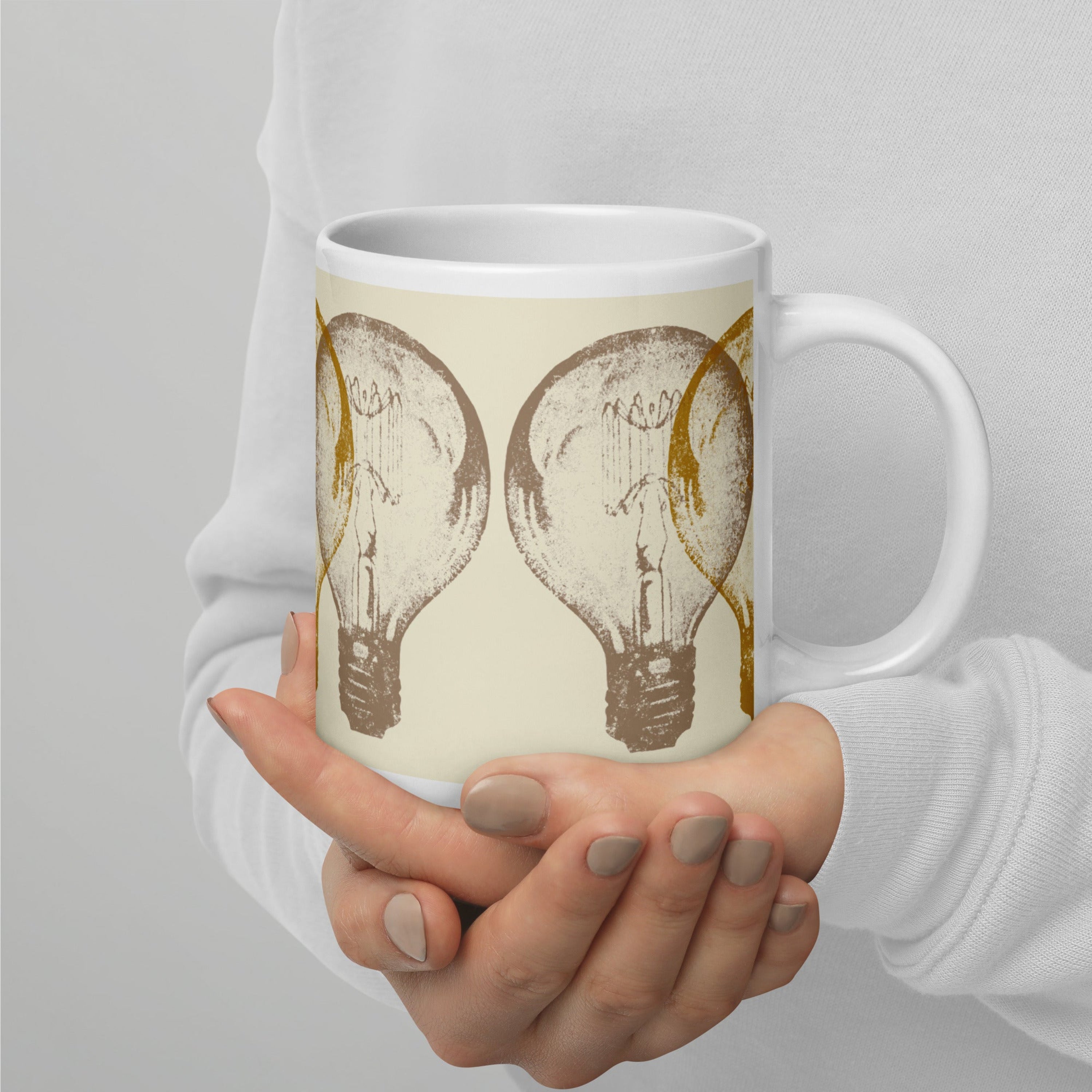 Person holding a mug with light bulb design against a gray background.